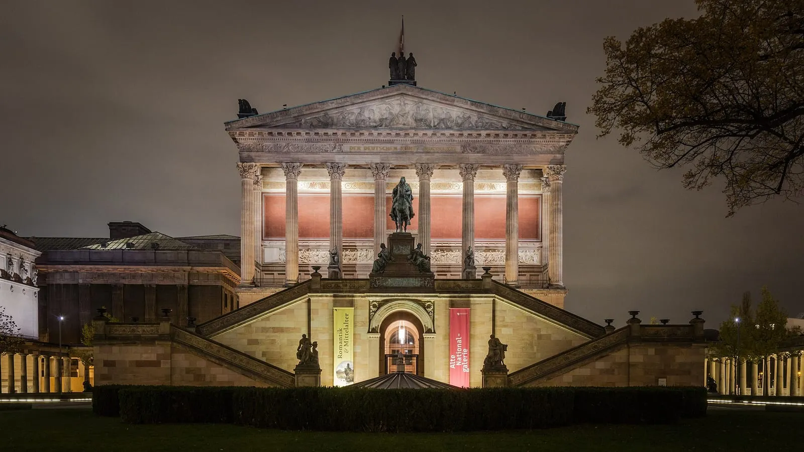 L'Alte Nationalgalerie illuminée de nuit sur l'île aux musées, avec sa statue équestre devant l'escalier du portique