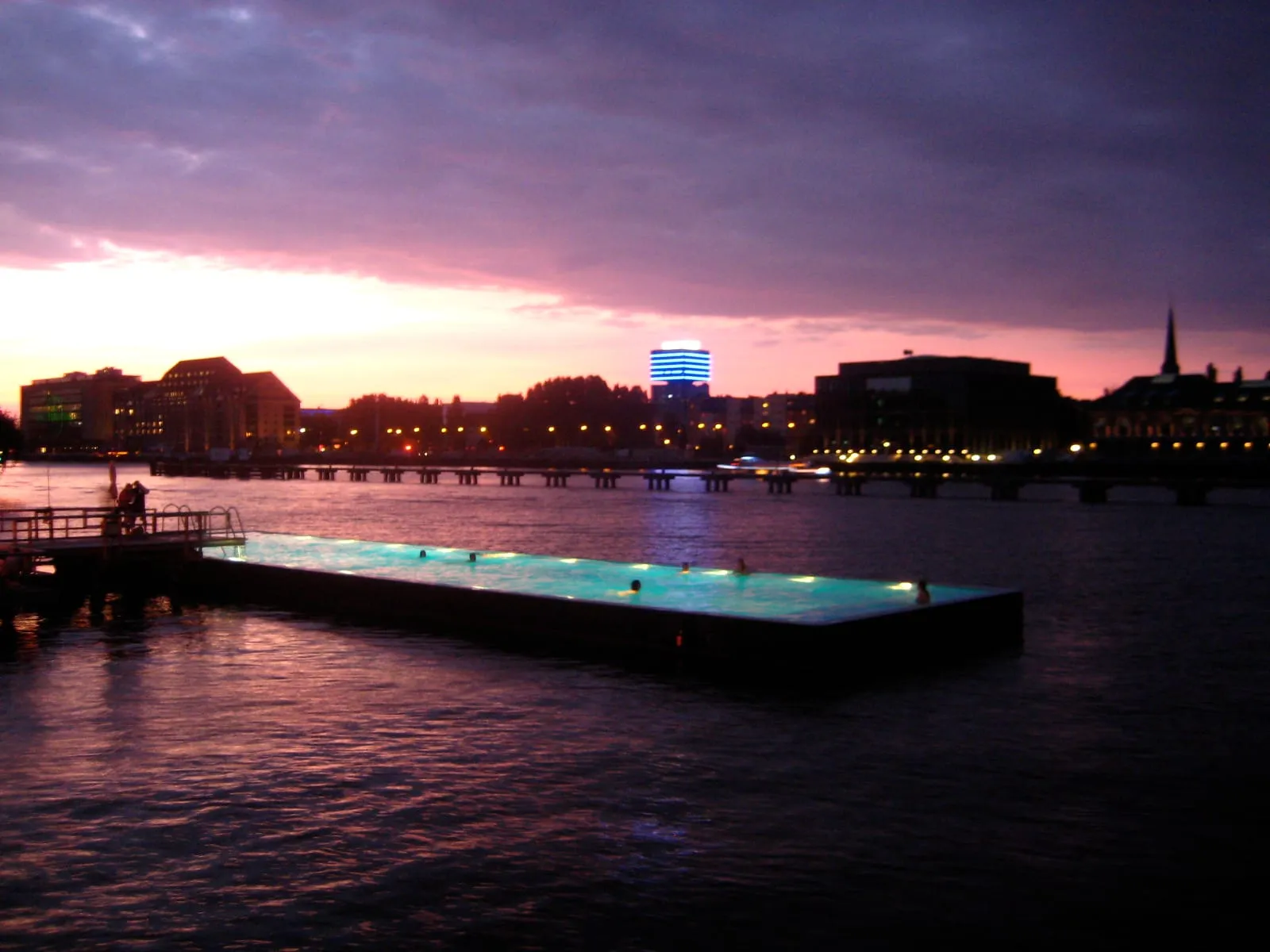 Le Badeschiff au coucher du soleil, piscine flottante illuminée sur la Spree avec des nageurs