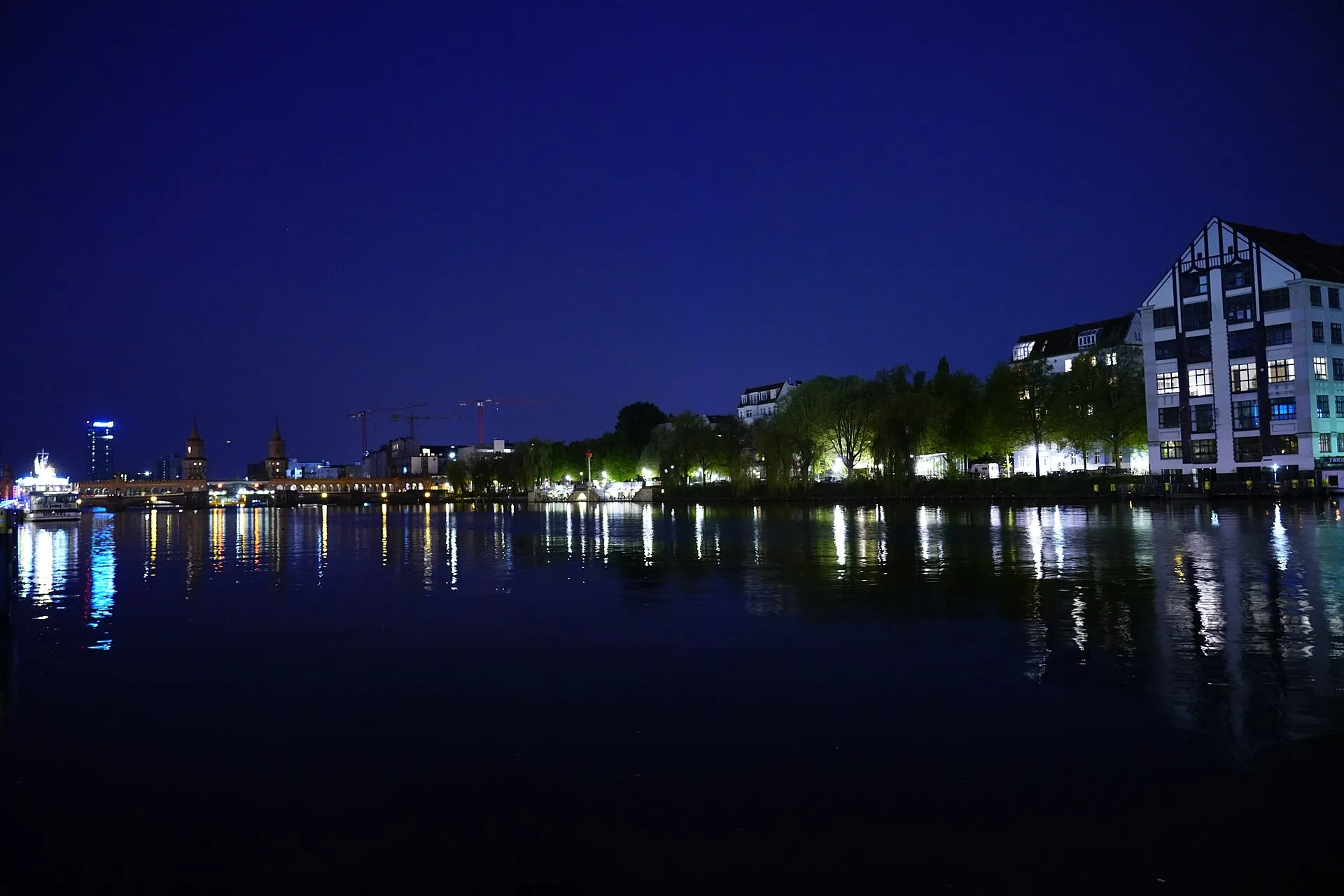 L'Oberbaumbrücke illuminé la nuit, ses deux tours de brique rouge se reflétant dans les eaux calmes de la Spree