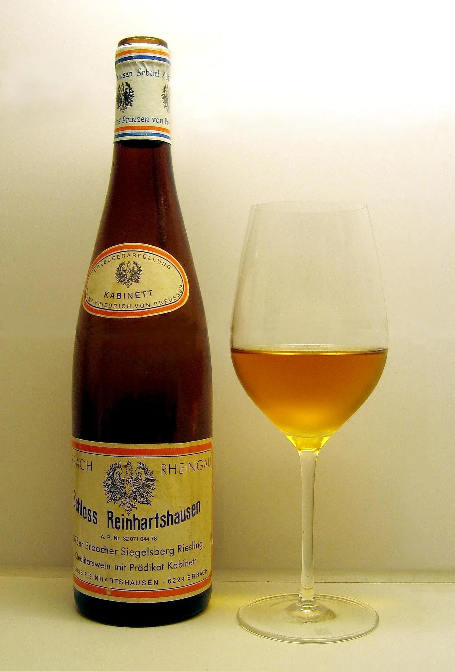 Une bouteille de riesling du Rheingau et un verre de vin blanc ambré sur une table claire
