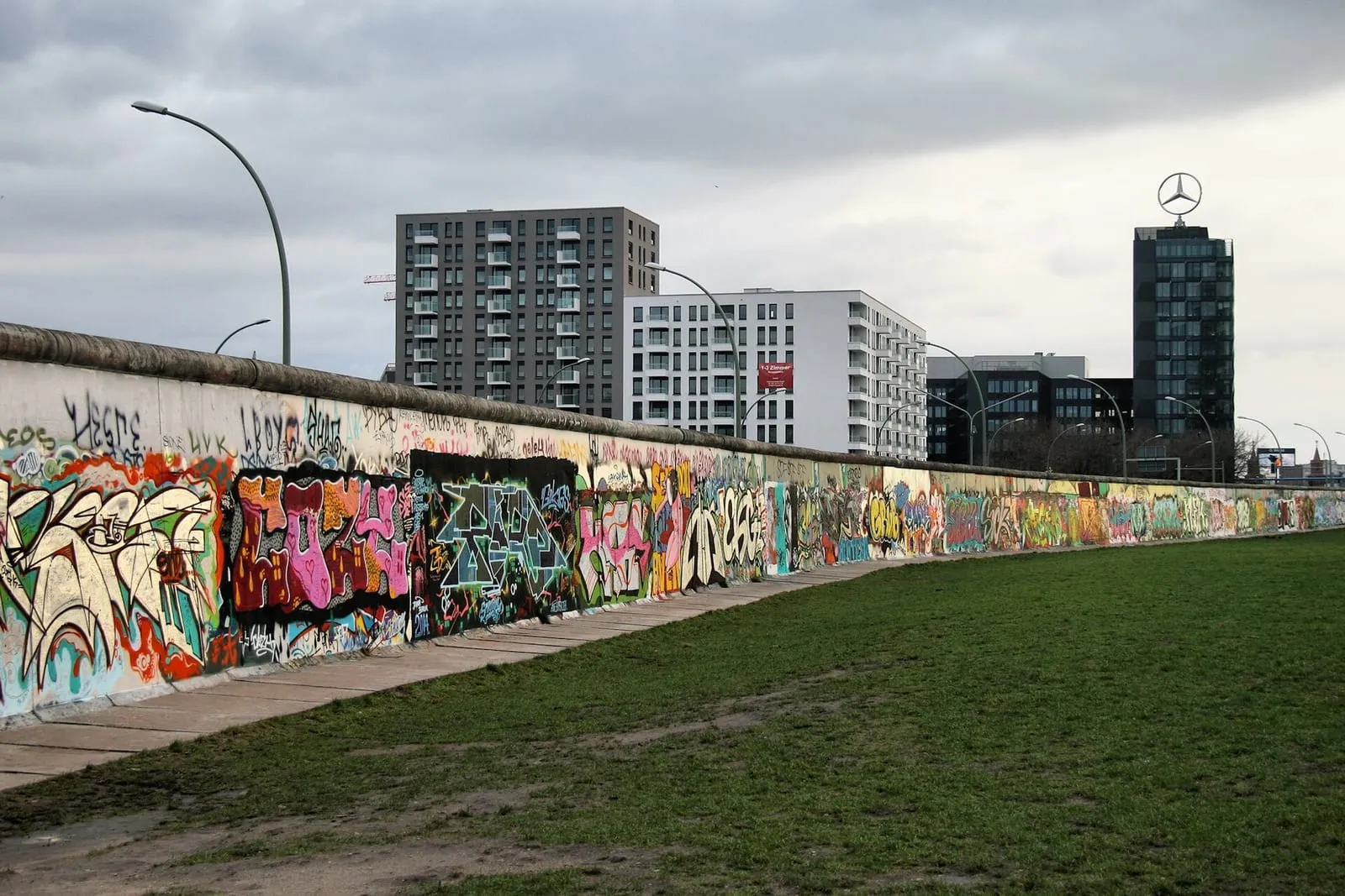Le mur de Berlin le long de la Mühlenstraße, couvert de graffitis, avec la tour du Park Inn en arrière-plan