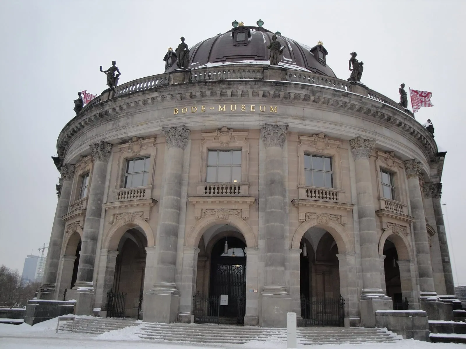 La façade courbe du Bode-Museum sous la neige, sa coupole et ses statues découpées sur un ciel d'hiver gris