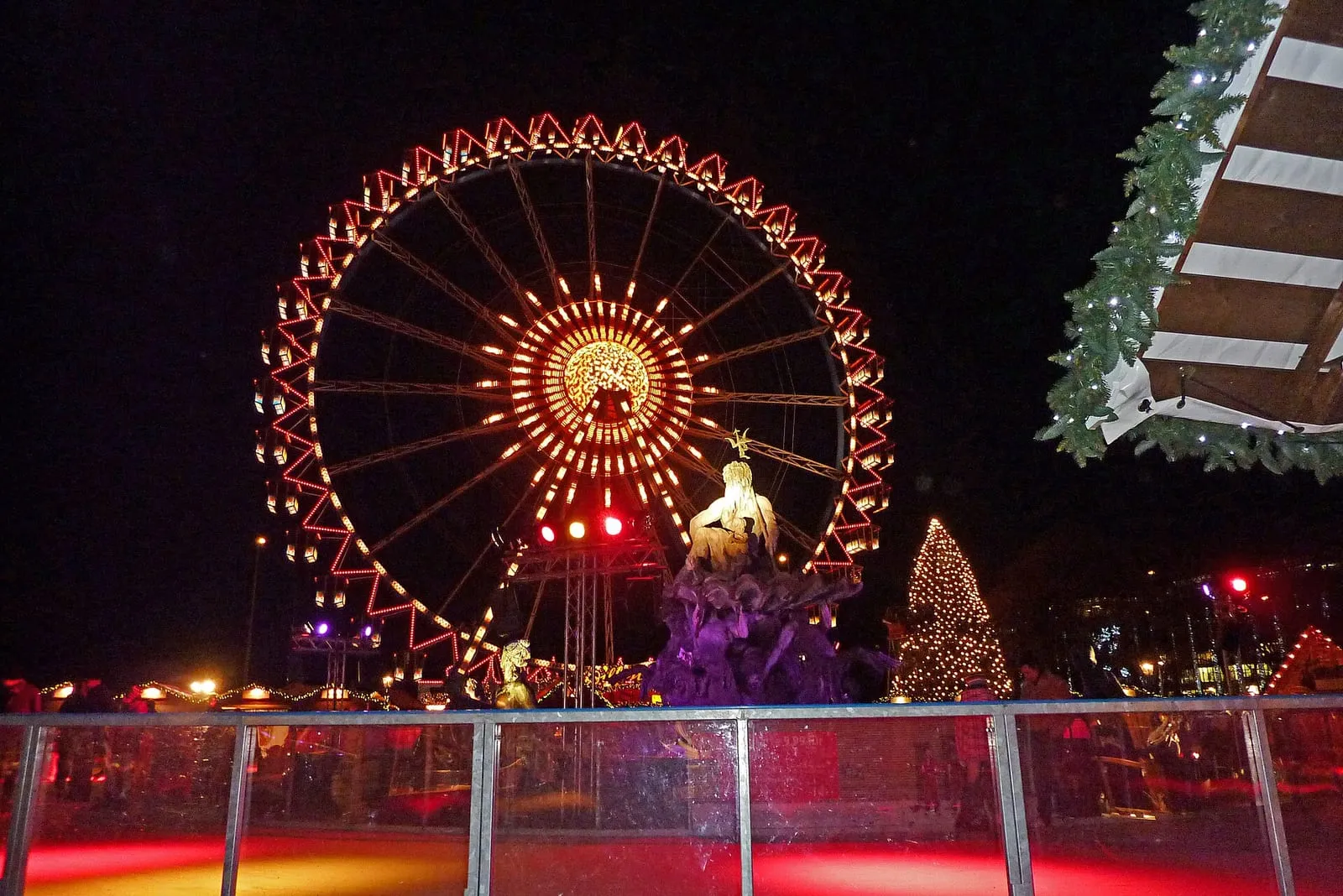 La patinoire du marché de Noël devant l'hôtel de ville de Berlin, la grande roue illuminée et la fontaine de Neptune en arrière-plan
