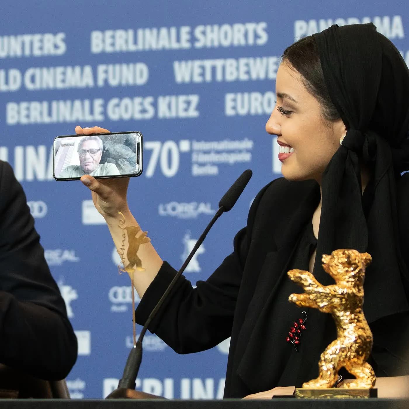 Un lauréat tient l'Ours d'or, la statuette du prix principal de la Berlinale, devant les photographes