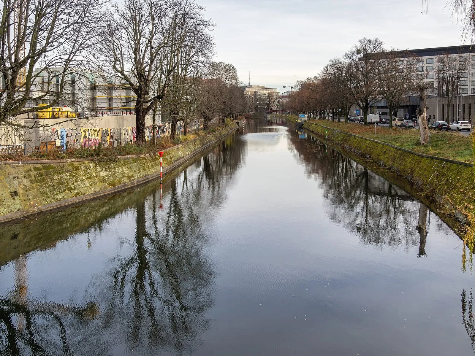 Le Landwehrkanal en hiver, ses berges enneigées plantées d'arbres nus et un mur de berge couvert de graffitis