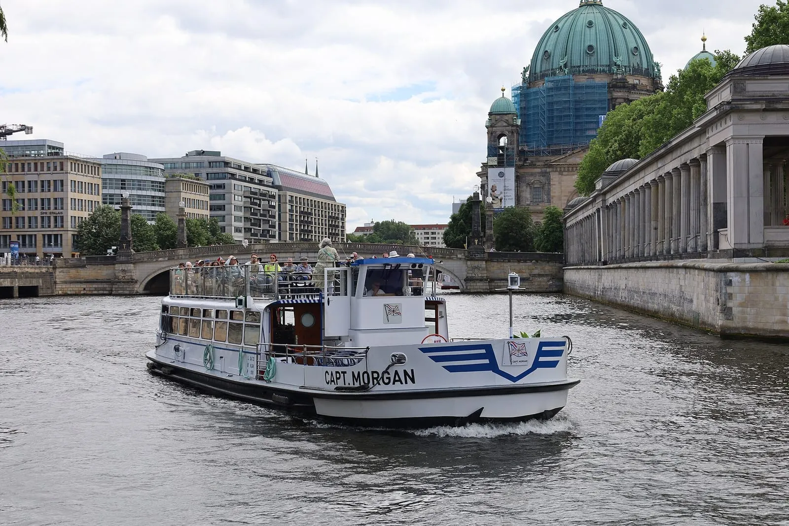 Un bateau-promenade blanc quittant le ponton devant la coupole de la cathédrale de Berlin et les colonnades de l'île aux musées