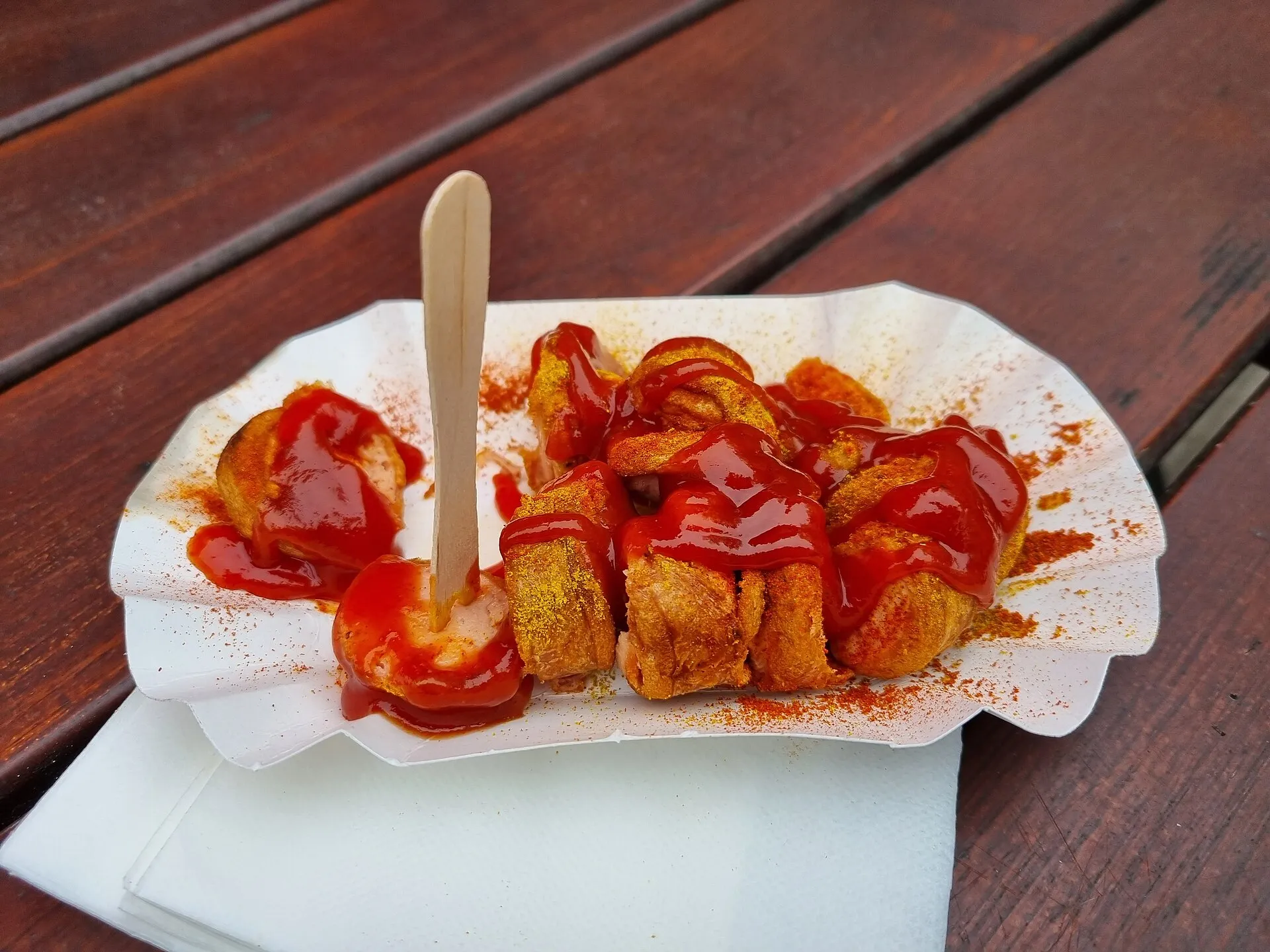 Une currywurst berlinoise coupée en rondelles, nappée de sauce tomate au curry et saupoudrée de poudre de curry