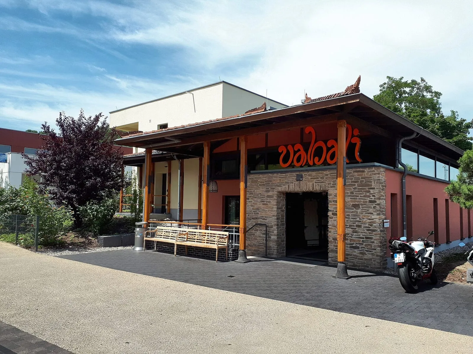 L'entrée du vabali spa à Moabit, son enseigne orange sur un mur de pierre et son porche en bois