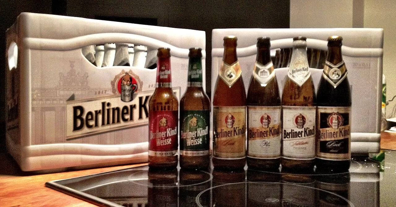 Des bouteilles de bières Berliner Kindl, de la Berliner Weisse au pilsener, posées près d'une caisse à l'écusson de la brasserie