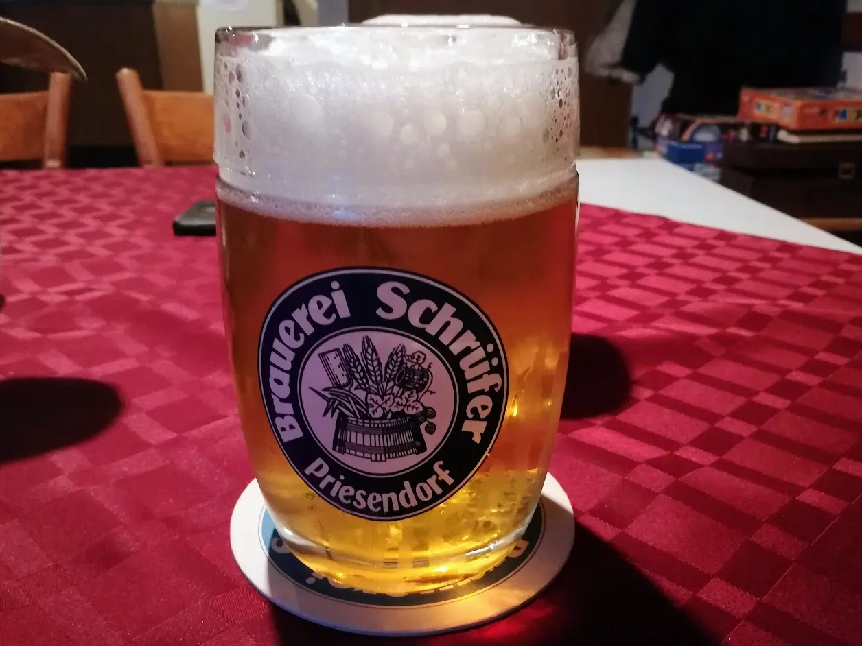 Un verre de helles, bière blonde allemande, servi avec une épaisse mousse sur une table de brasserie