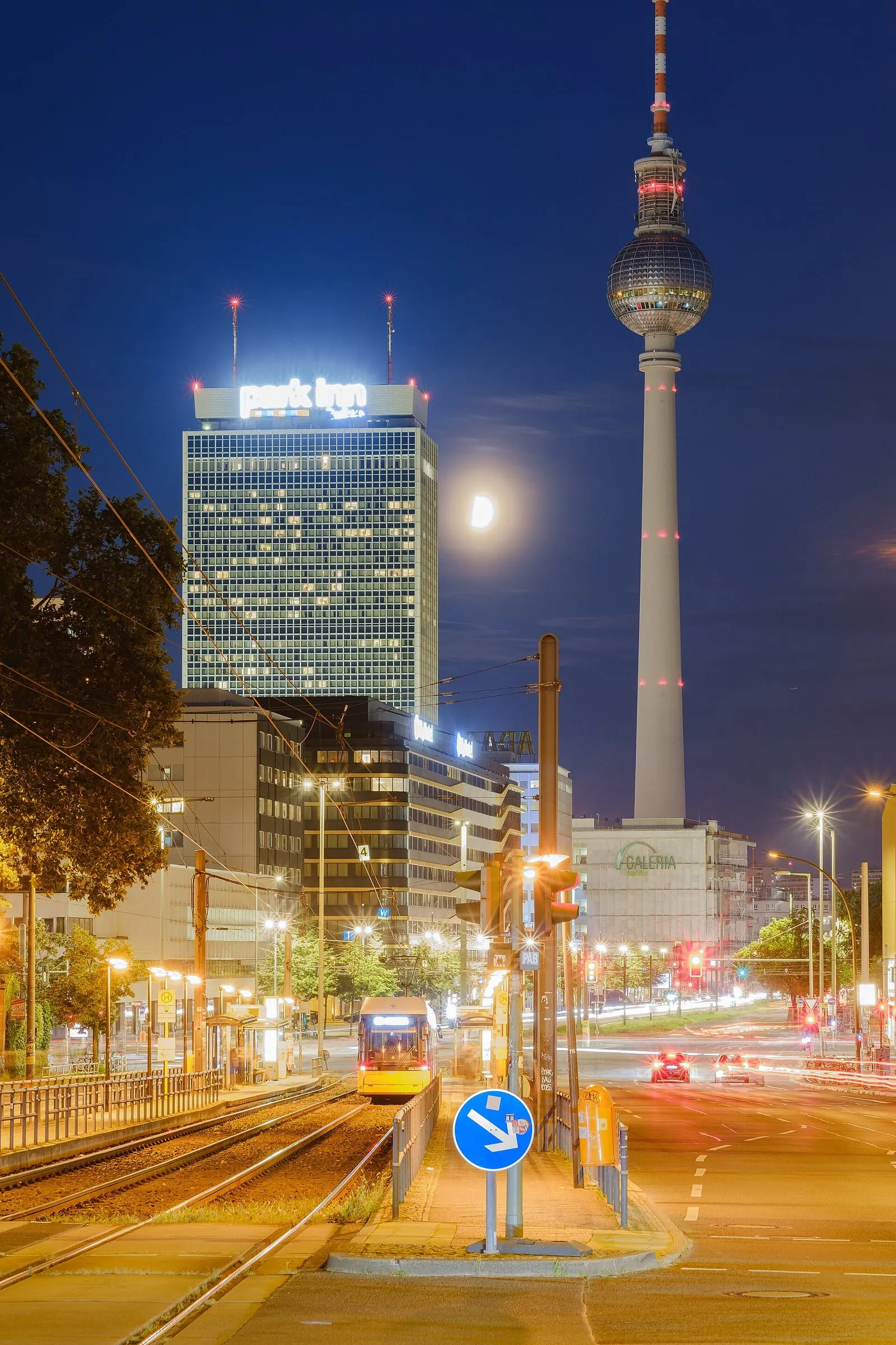 La tour de télévision de Berlin éclairée la nuit près de l'Alexanderplatz, sphère lumineuse et Park Inn à gauche sous un ciel bleu sombre
