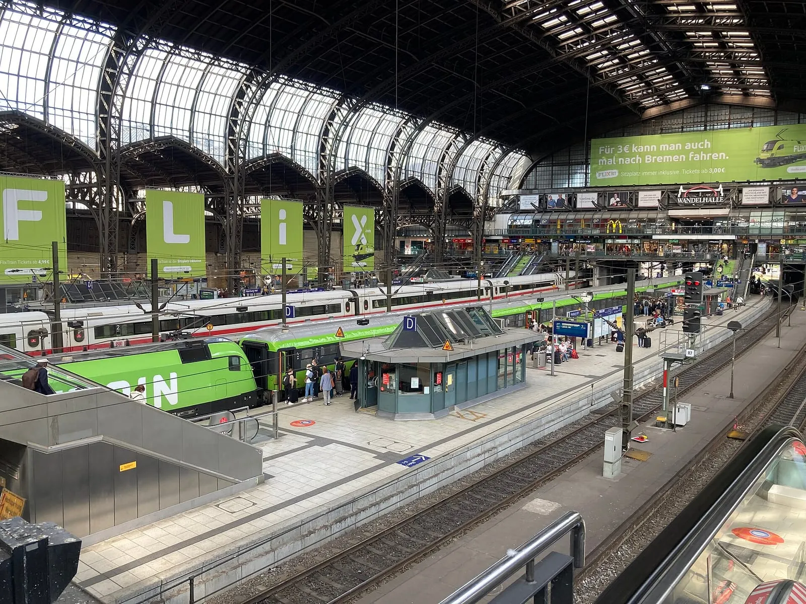 Un train Flixtrain en gare de Hambourg, devant une publicité pour la liaison vers Brême