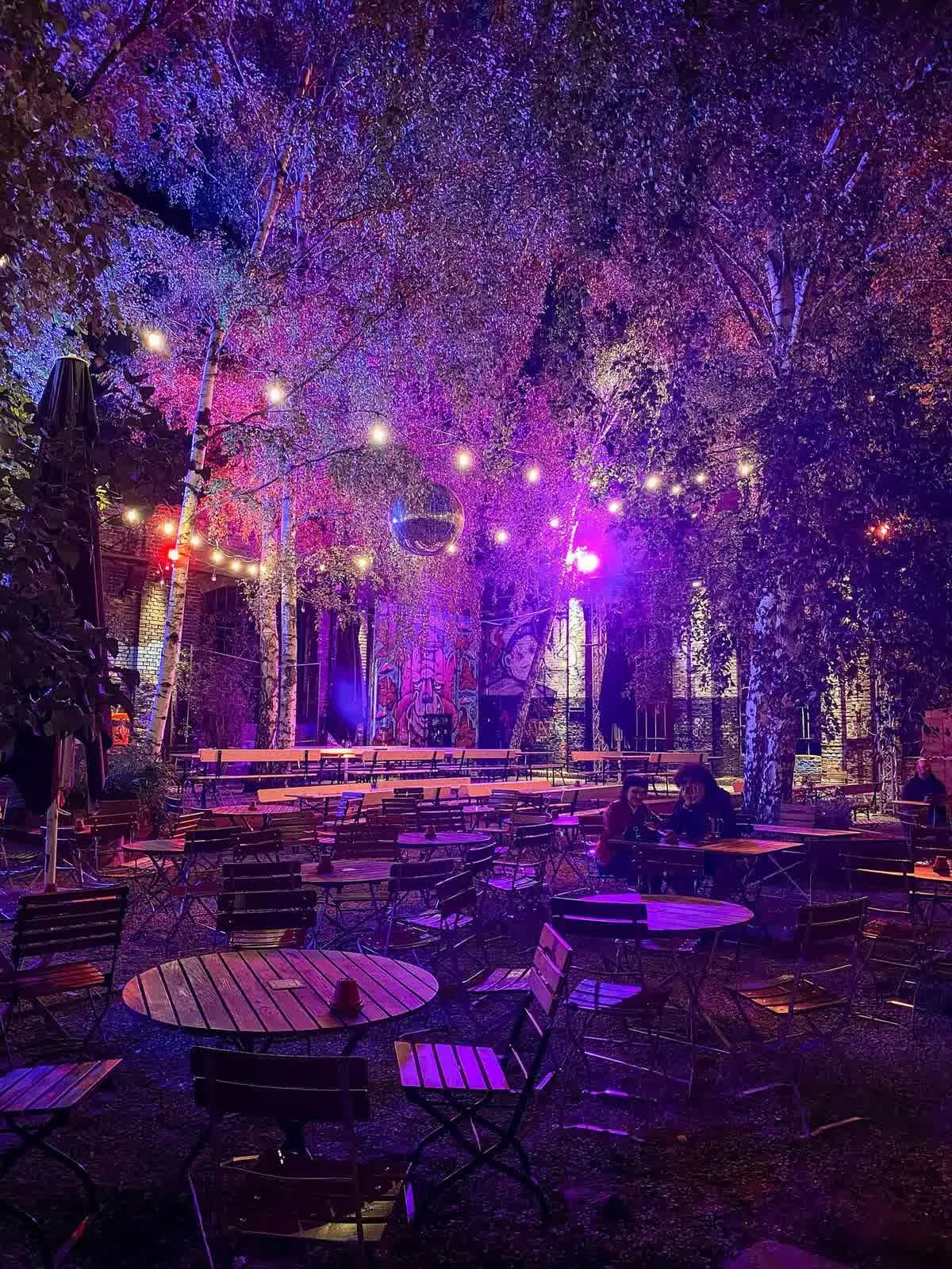 Une cour du RAW-Gelände en soirée, entre terrasses de bar et murs couverts de graffitis