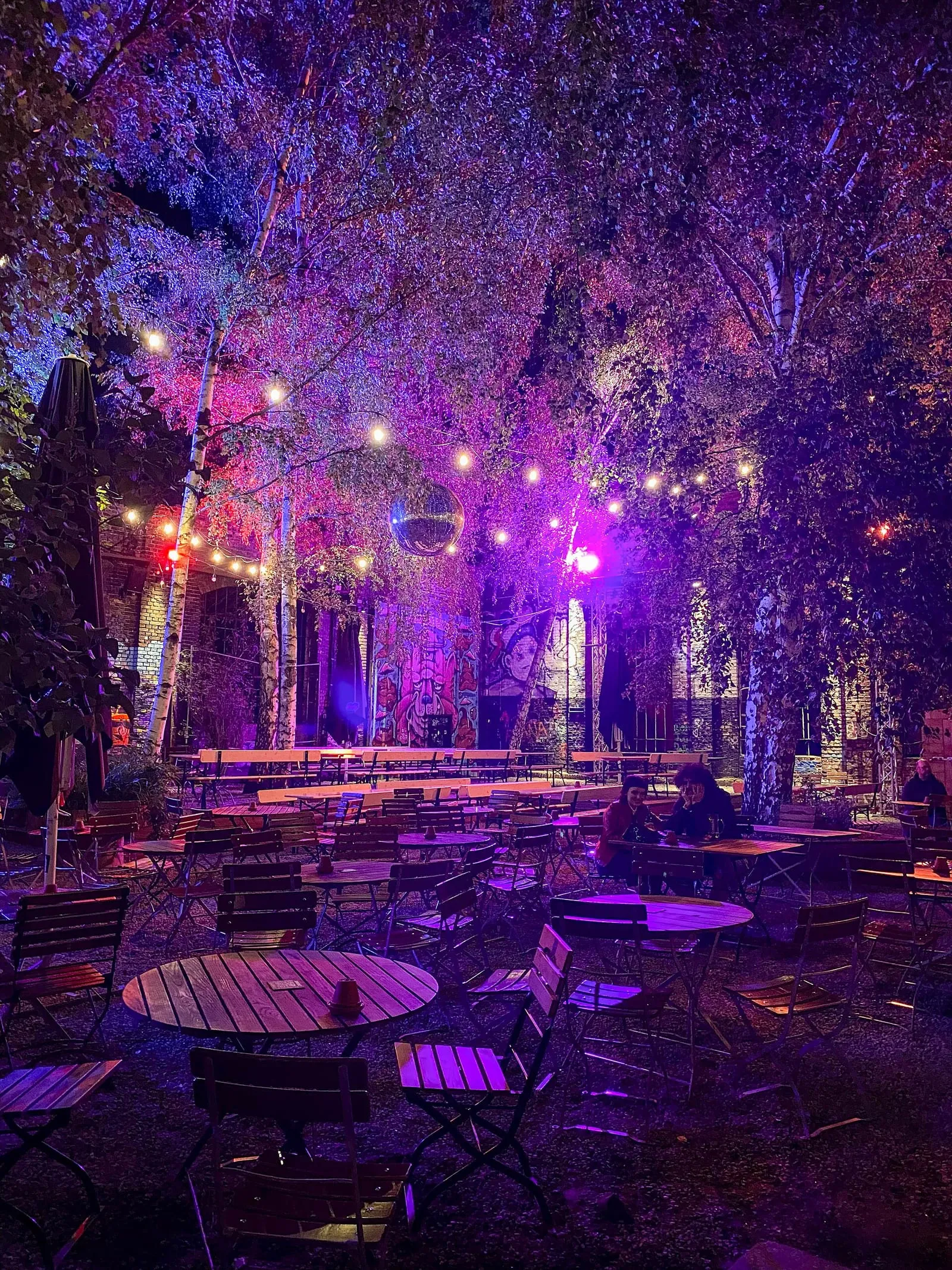 Une cour du RAW-Gelände en soirée, entre terrasses de bar et murs couverts de graffitis