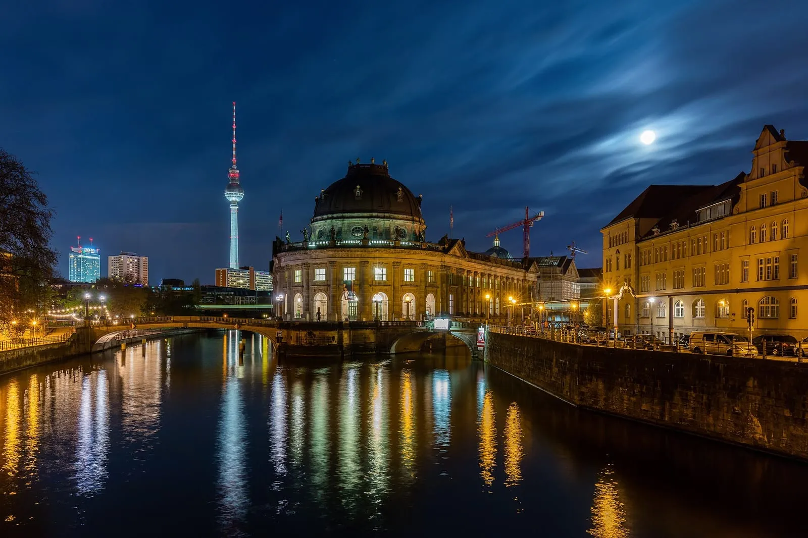 Le Bode-Museum illuminé au crépuscule sur l'île aux musées, sa coupole au-dessus de la Spree et la tour de télévision en arrière-plan