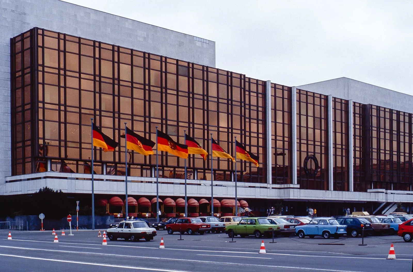 Le Palast der Republik vers 1990, façade de verre bronze et drapeaux est-allemands devant l'entrée