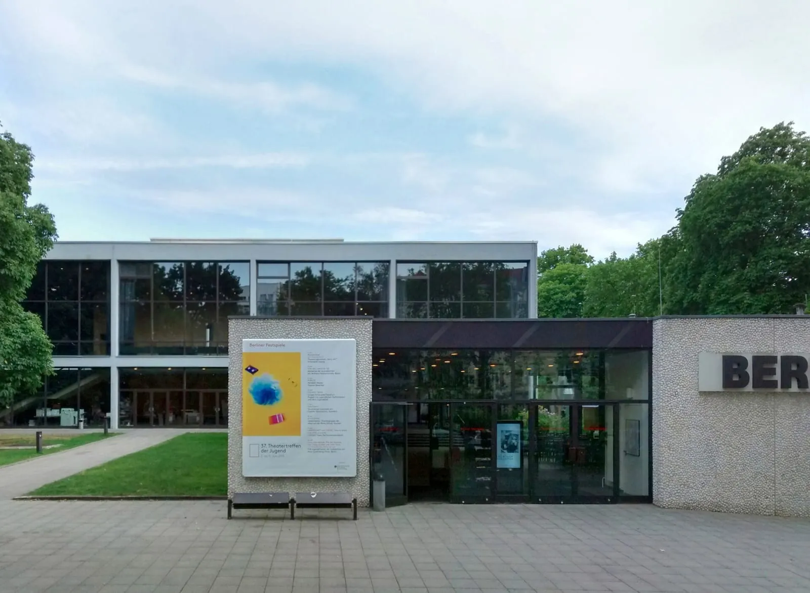 L'entrée du Haus der Berliner Festspiele à Wilmersdorf : façade vitrée des années 1960, affiche des Berliner Festspiele sur le parvis pavé