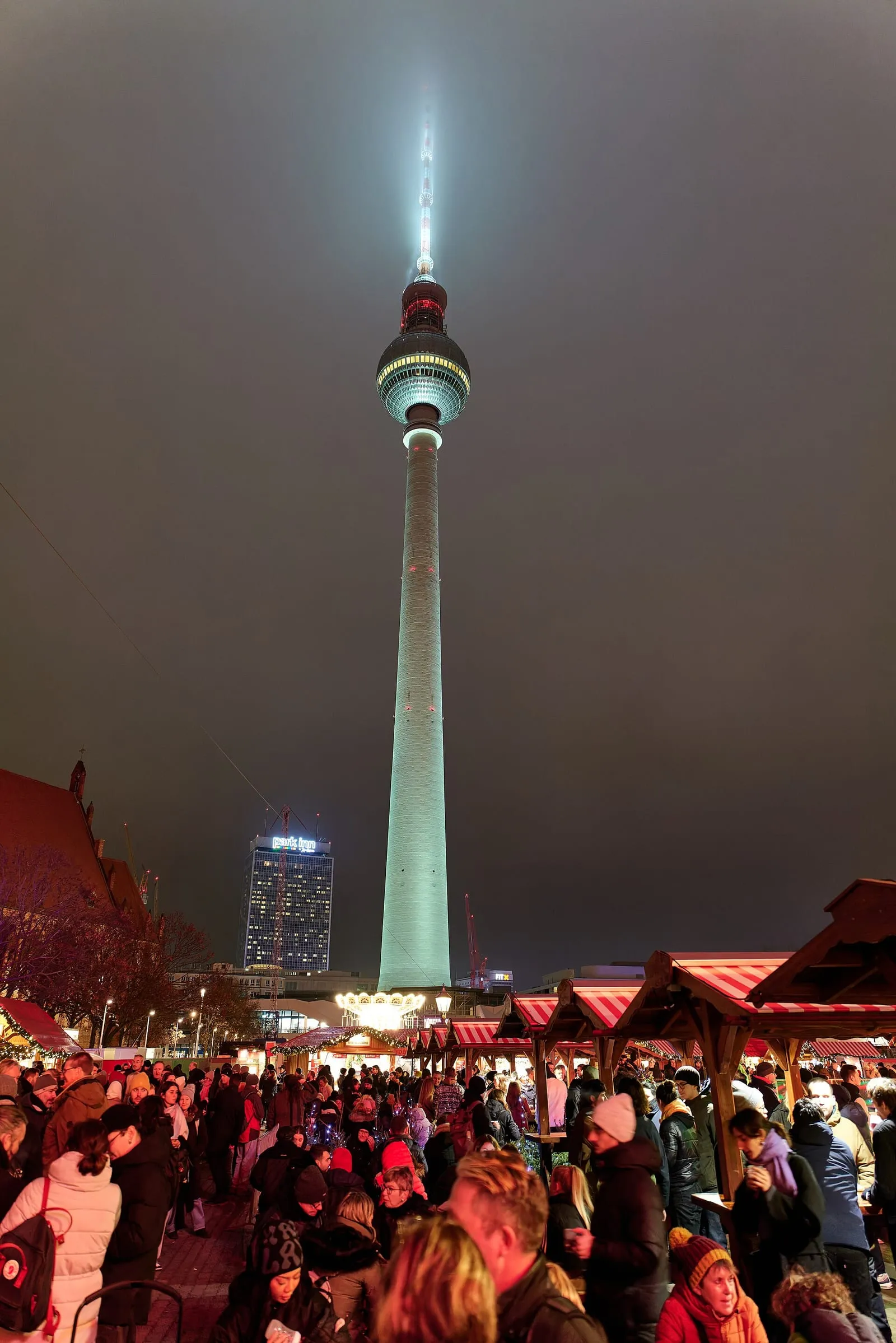 Marché de Noël de nuit devant le Rotes Rathaus, stands à toit rayé rouge et blanc, tour de la Fernsehturm illuminée en arrière-plan
