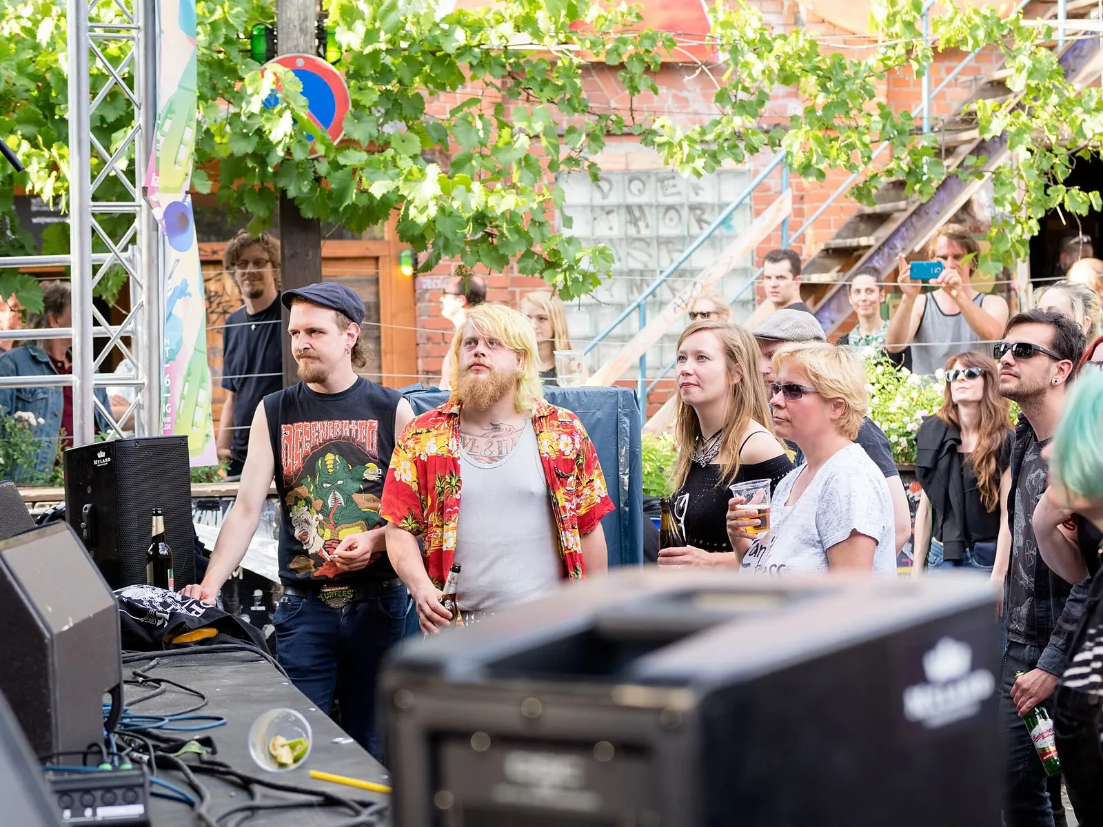 Public rassemblé devant une scène de fortune lors d'un concert gratuit de la Fête de la musique à Berlin, console de mixage et fût de bière au premier plan