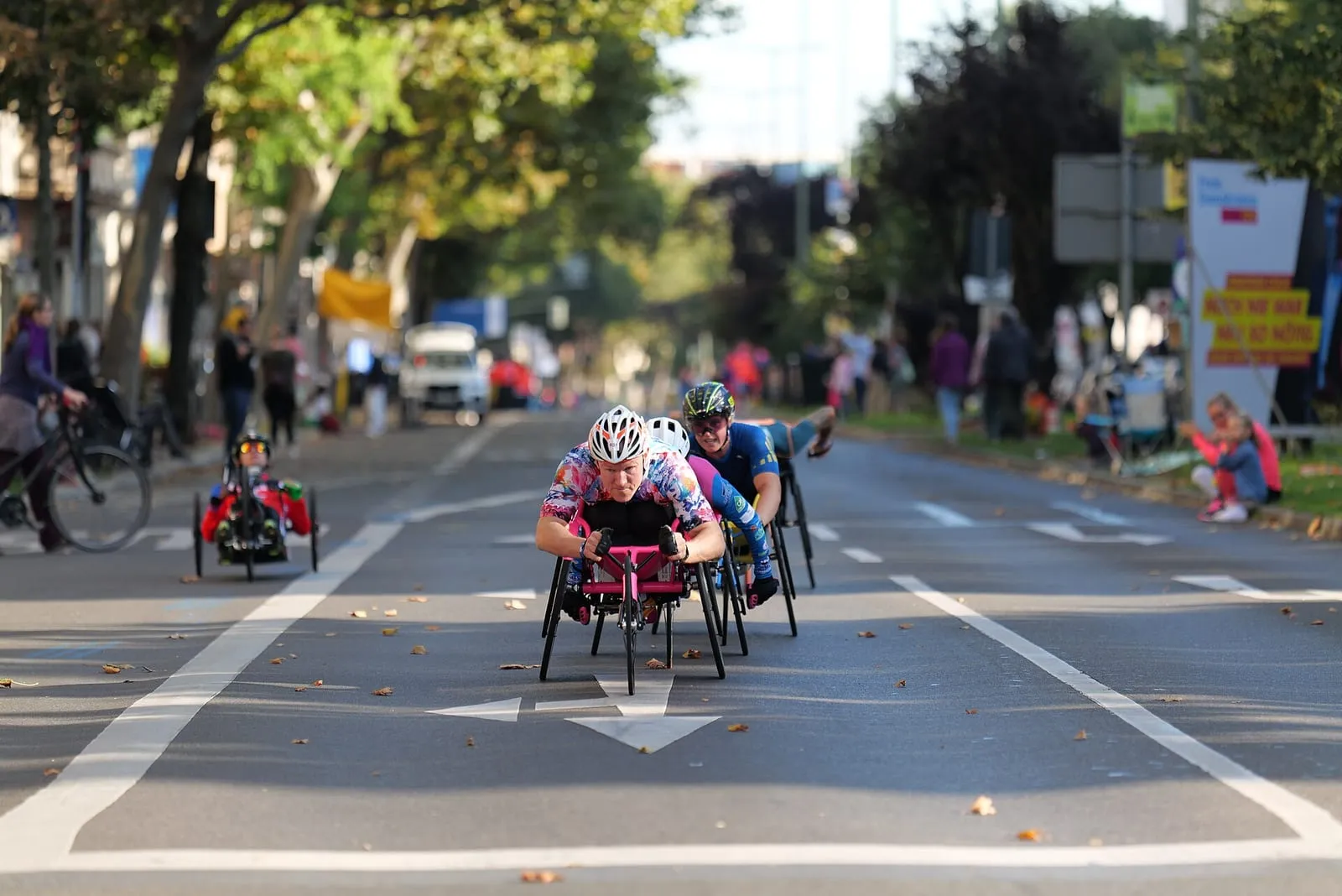 Athlètes en fauteuil roulant et en handbike dans une rue de Berlin pendant le marathon, public derrière les barrières