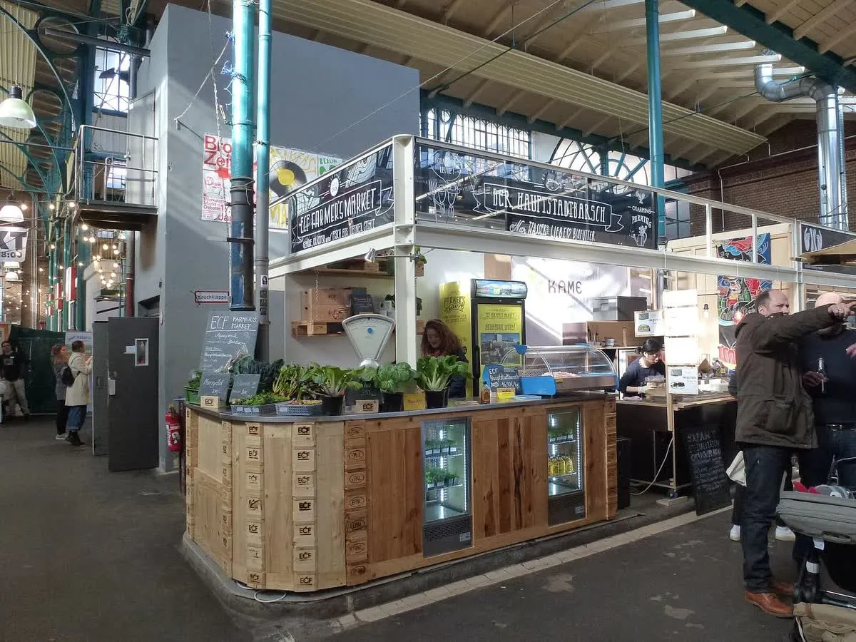 Un stand de marché sous la charpente métallique de la Markthalle Neun