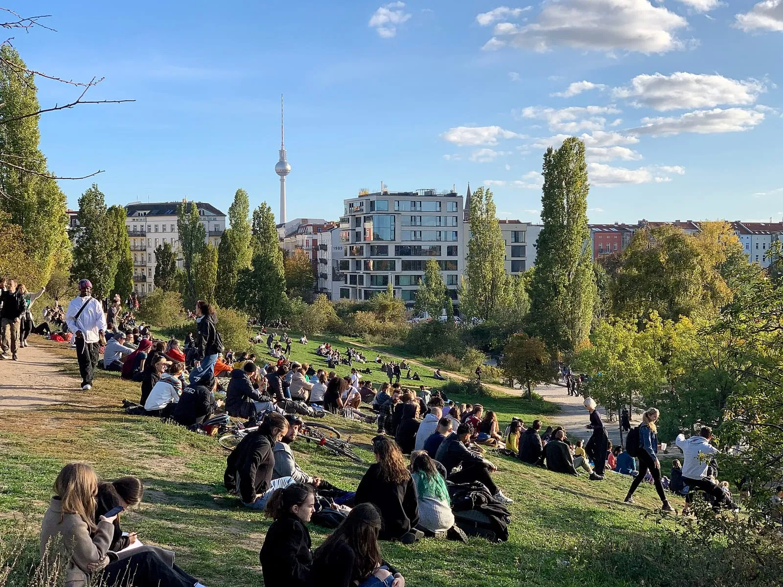 La pelouse du Mauerpark remplie de promeneurs un jour de beau temps, avec la tour de télévision en arrière-plan