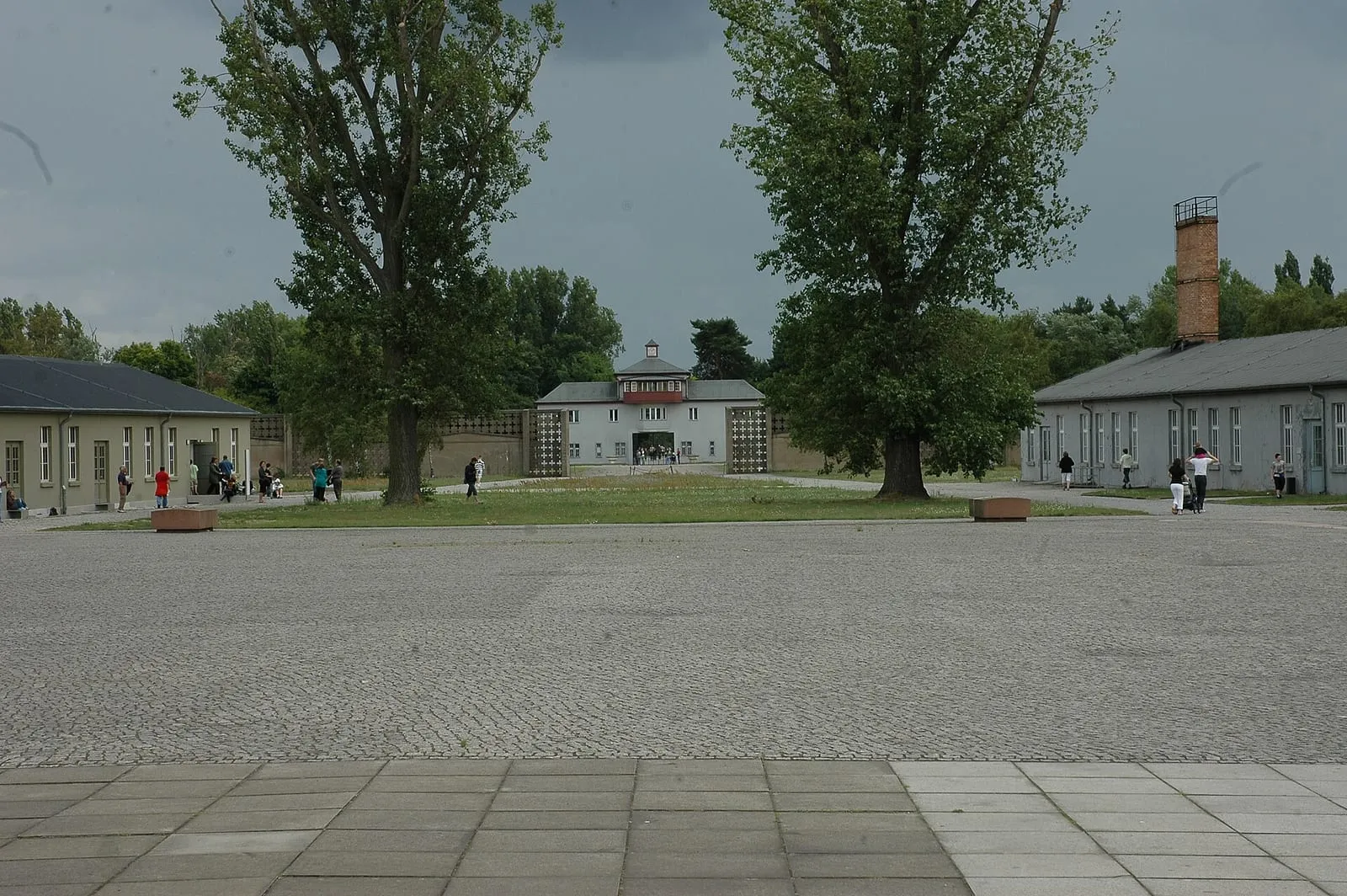 La place d'appel du camp, son pavement de pierre, les pavillons qui la bordent et la porte d'entrée au fond
