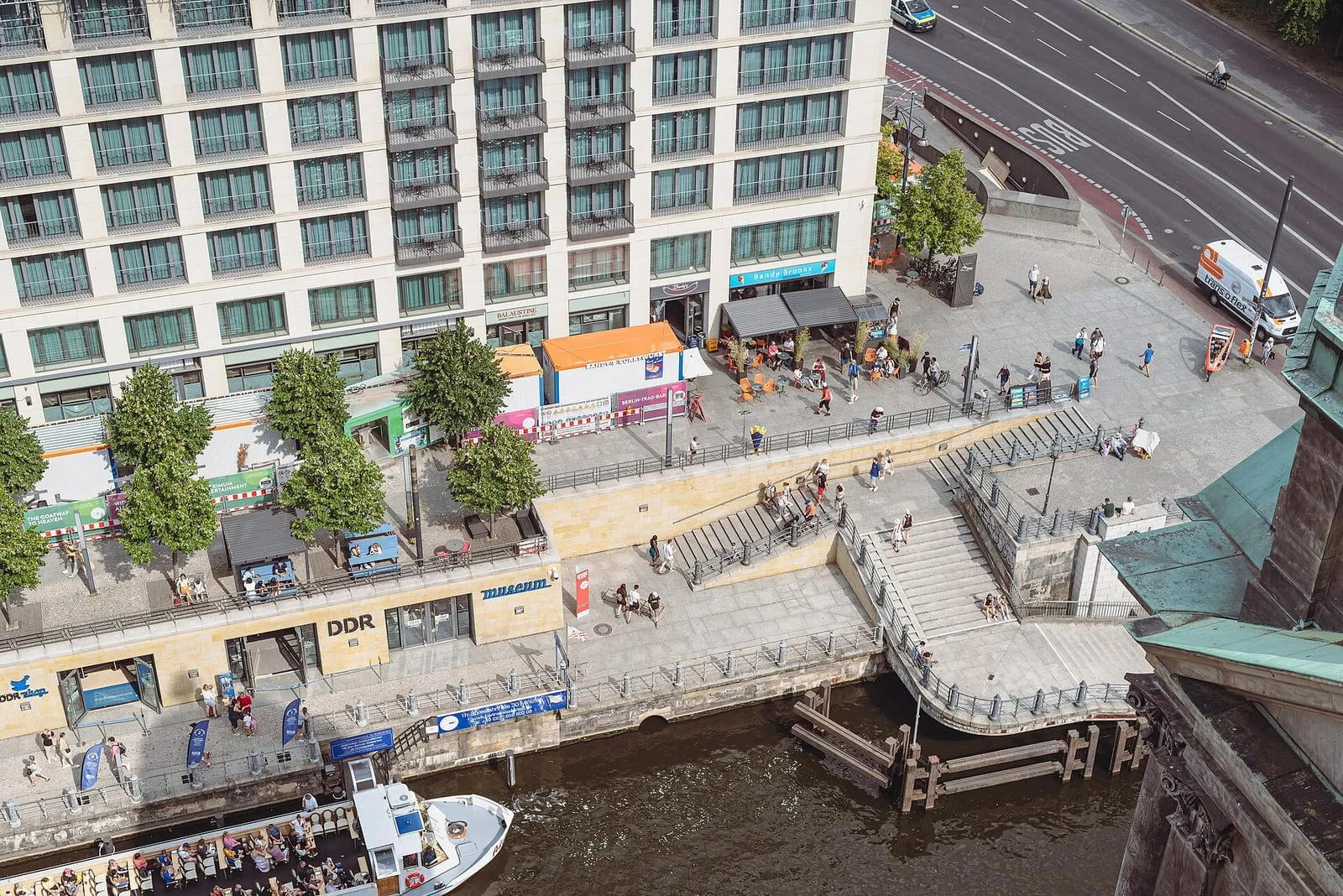 Le DDR Museum au bord de la Spree vu depuis la coupole de la cathédrale de Berlin : l'enseigne DDR, les escaliers de la promenade et un bateau sur le fleuve