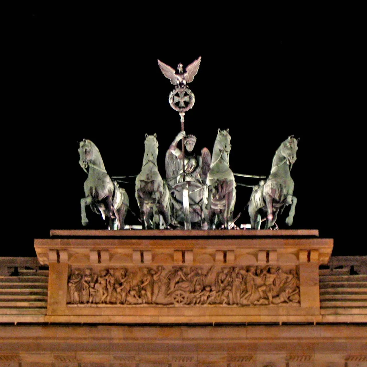 La quadrige de la porte de Brandebourg éclairée la nuit, avec la Victoire tenant un étendard surmonté de la croix de fer et de l'aigle au-dessus des quatre chevaux