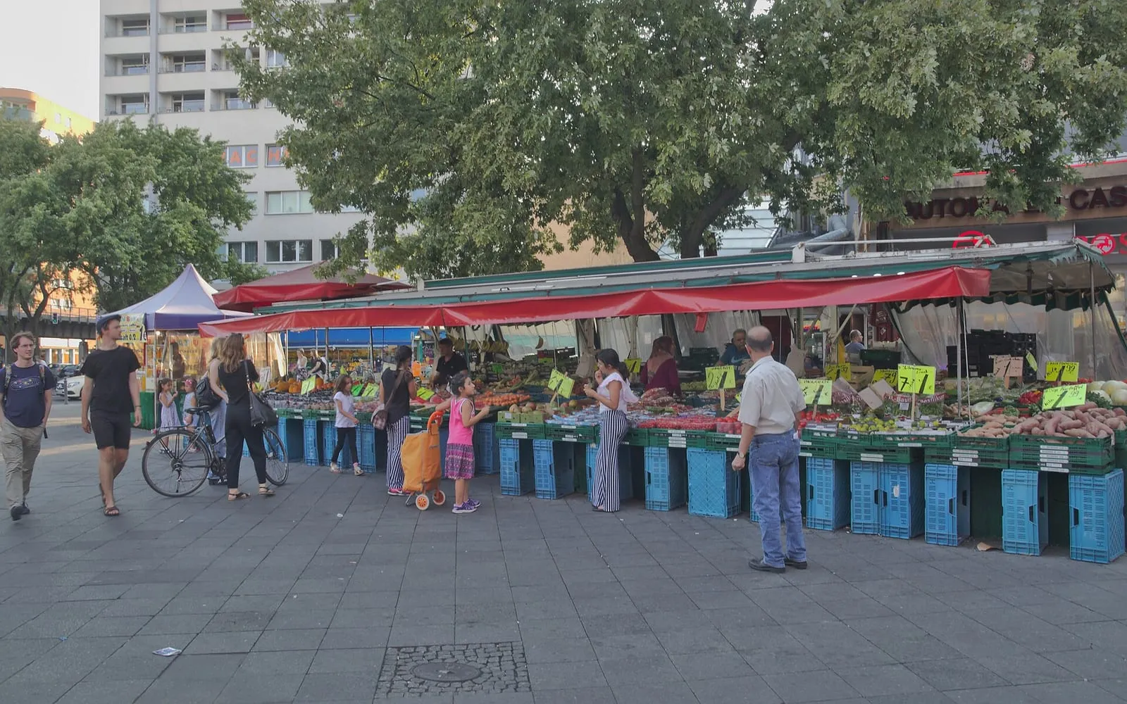 Le marché de fruits et légumes du Kottbusser Tor à Kreuzberg, ses étals sous bâche et ses cageots bleus devant les immeubles du quartier