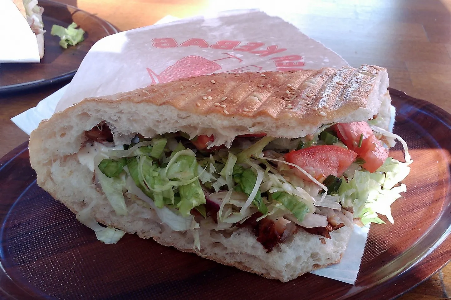 Un döner kebab berlinois garni de viande grillée, de salade et de sauce dans un pain plat