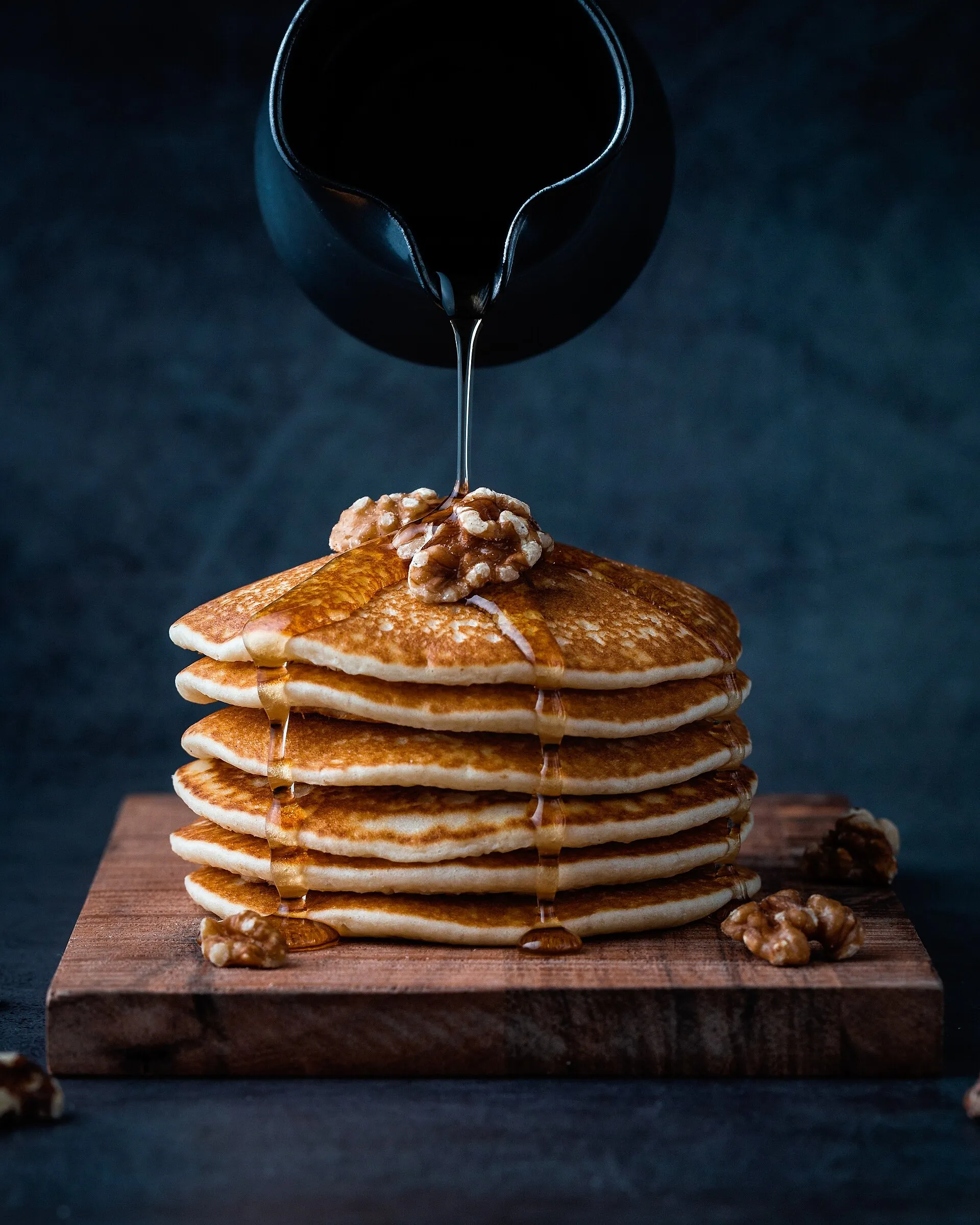 Pile de pancakes arrosée de miel et parsemée de noix