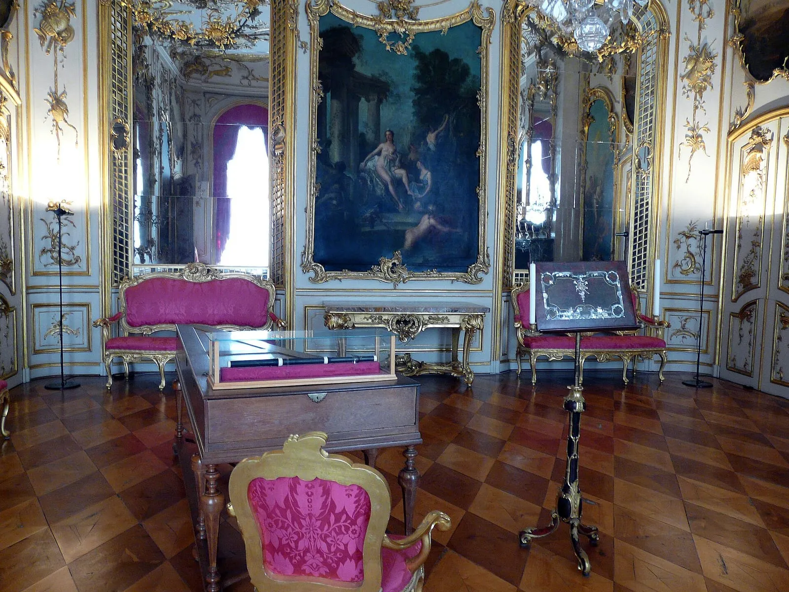 La salle de concert du palais de Sanssouci, boiseries blanches et dorées, grands miroirs et sièges tapissés de soie rose