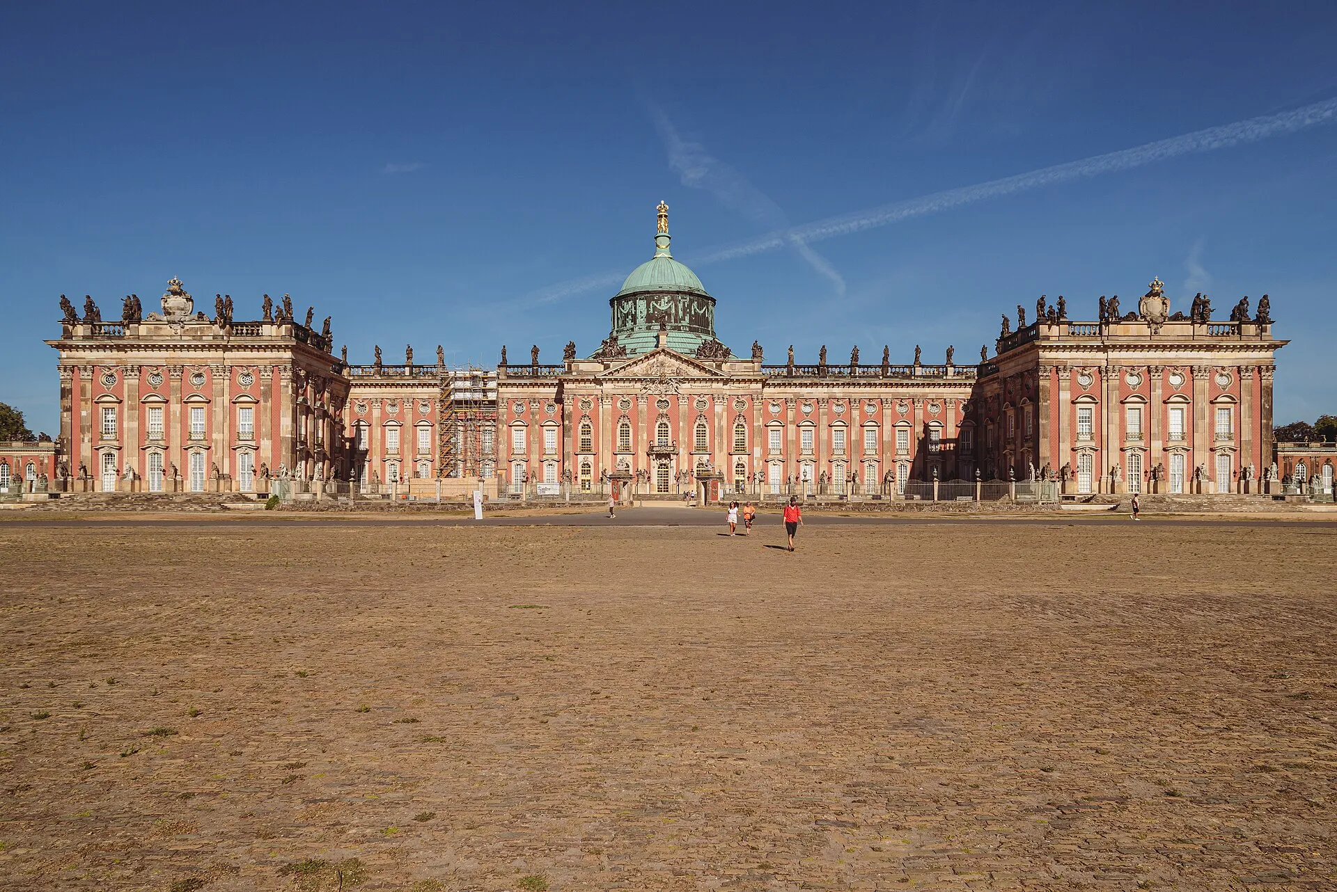 La longue façade rouge du Nouveau Palais de Potsdam et son dôme de cuivre vert, vus depuis l'esplanade