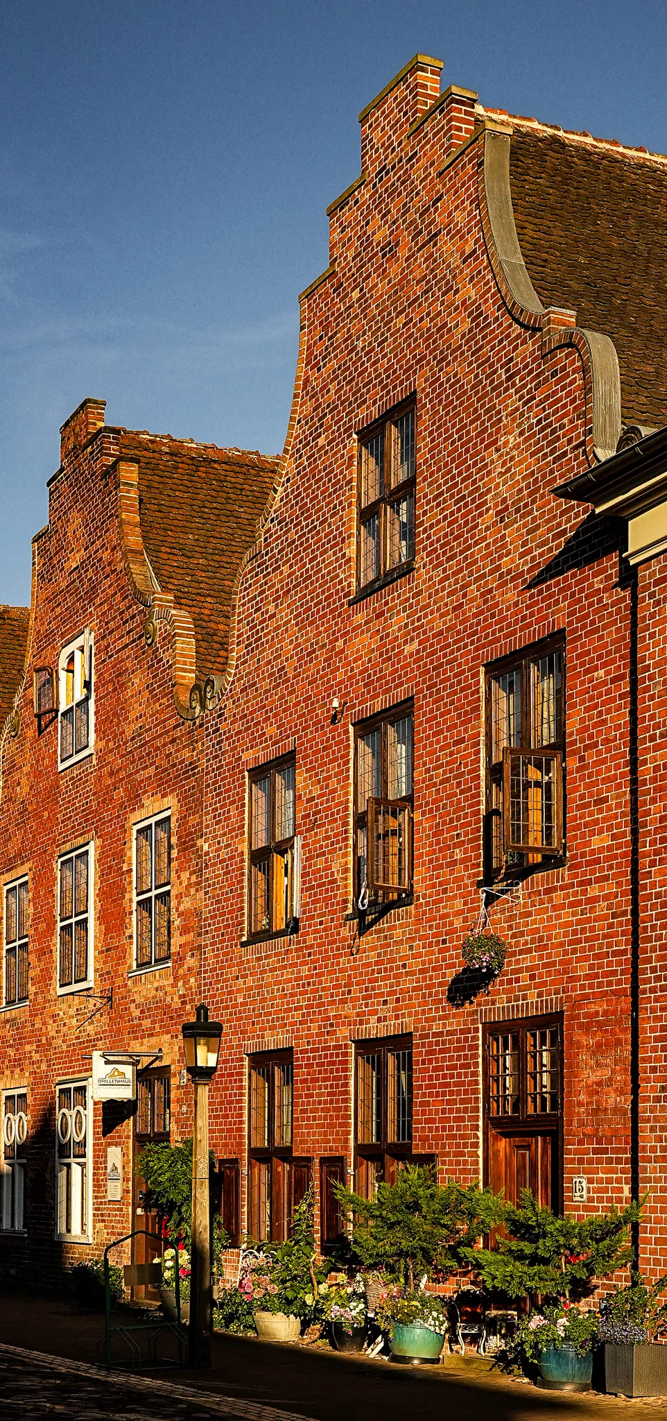 Façades de briques à pignon du quartier hollandais de Potsdam, éclairées en fin de journée, avec des pots de fleurs devant les fenêtres