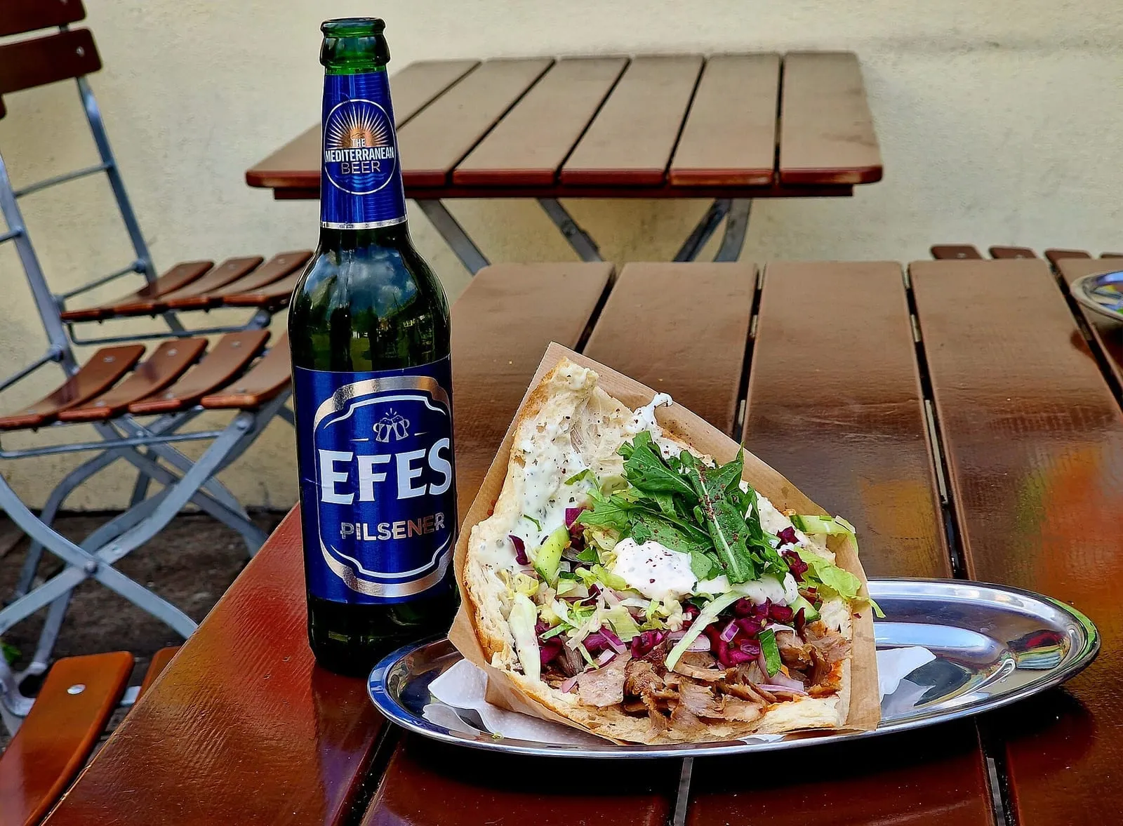 Un döner kebab généreusement garni, servi avec une bière sur la terrasse d’un restaurant berlinois
