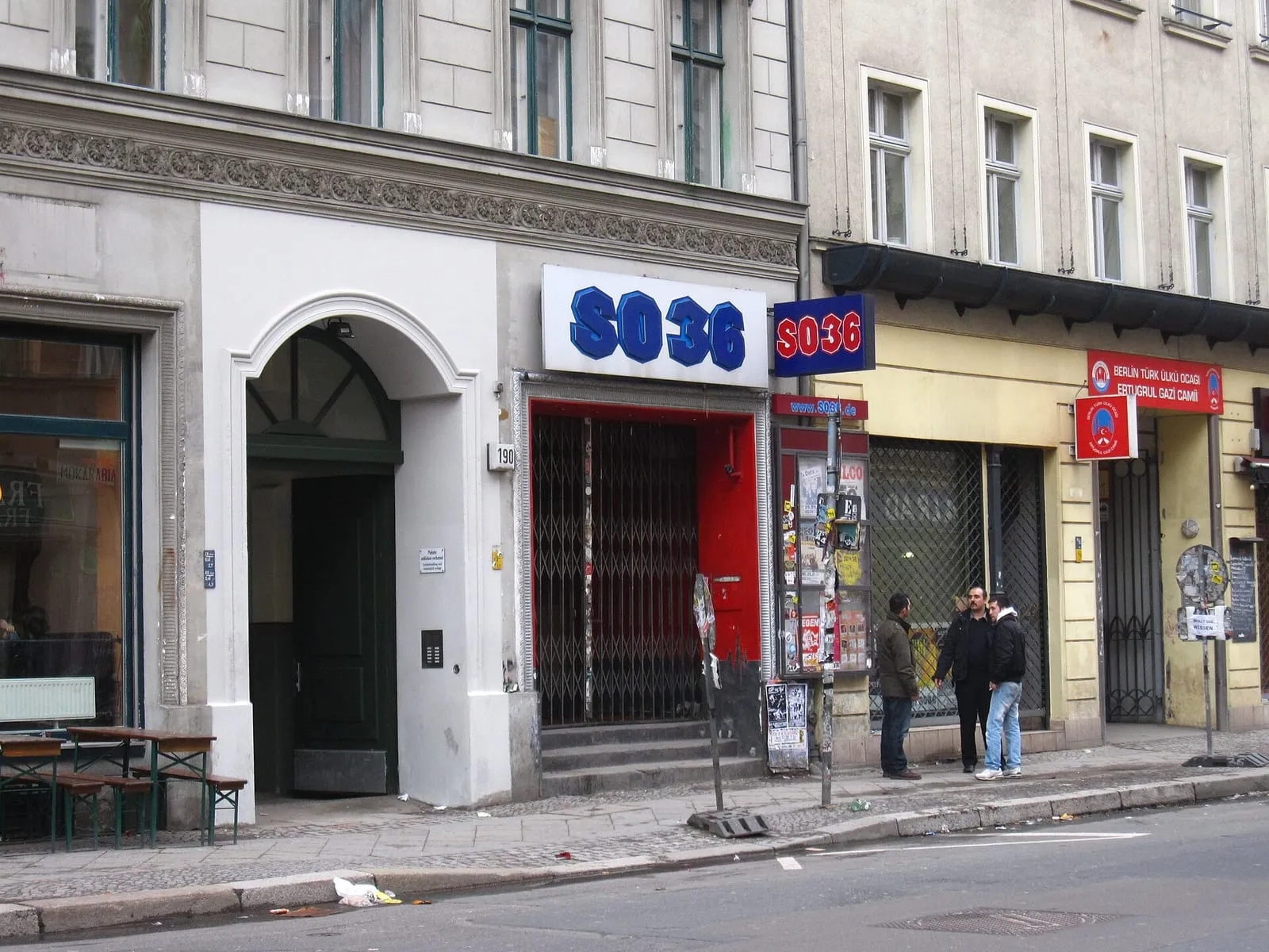 L'entrée du SO36 au 190 Oranienstraße à Kreuzberg, enseigne aux lettres bleues et rideau de fer baissé, le numéro 190 sur le pilier