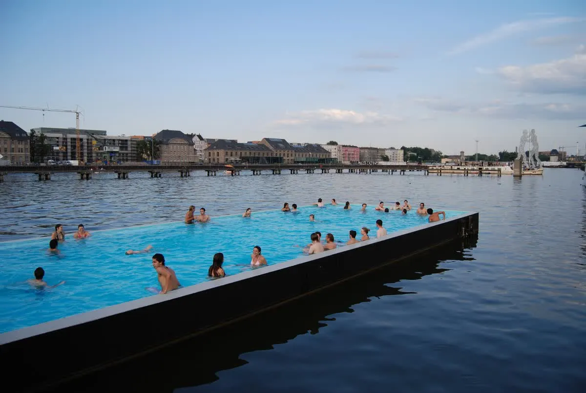 Le Badeschiff, piscine flottante amarrée dans la Spree à Berlin-Treptow, avec ses baigneurs et les immeubles de la ville en arrière-plan