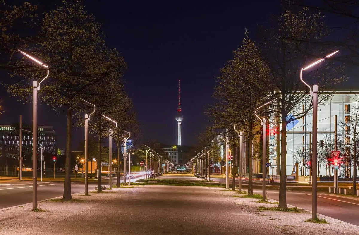 La tour de télévision de Berlin au bout d'une avenue bordée de réverbères, à la tombée de la nuit