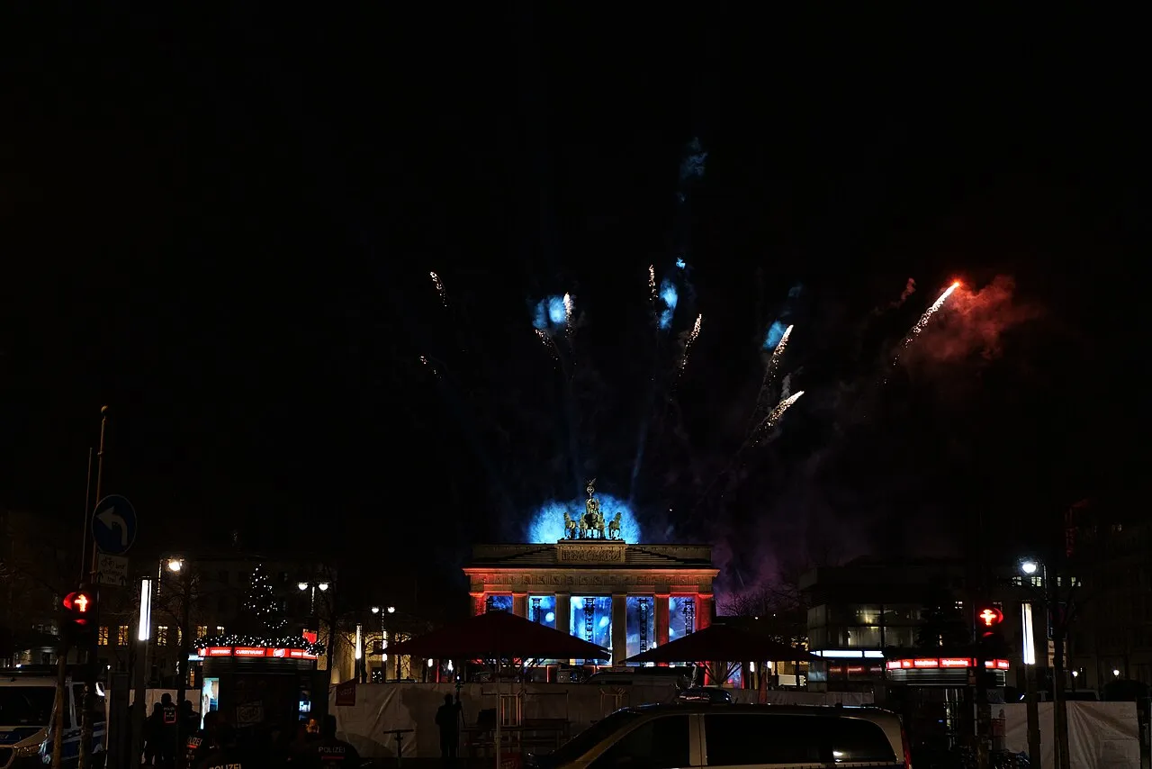 La porte de Brandebourg illuminée sous des feux d'artifice multicolores pendant la nuit du Nouvel An à Berlin