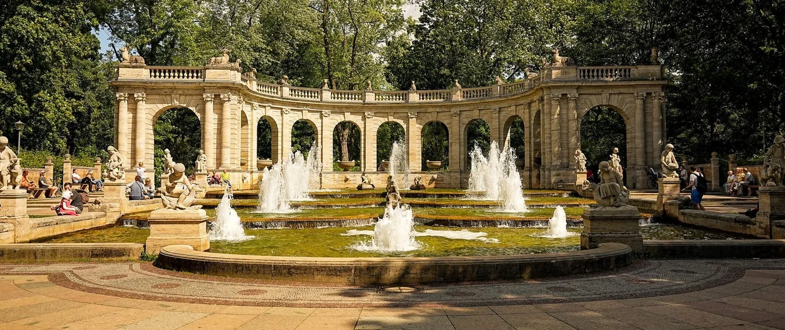 La fontaine des contes du Volkspark Friedrichshain, avec ses bassins, ses statues et son arcade de pierre claire, anime l'entrée du parc