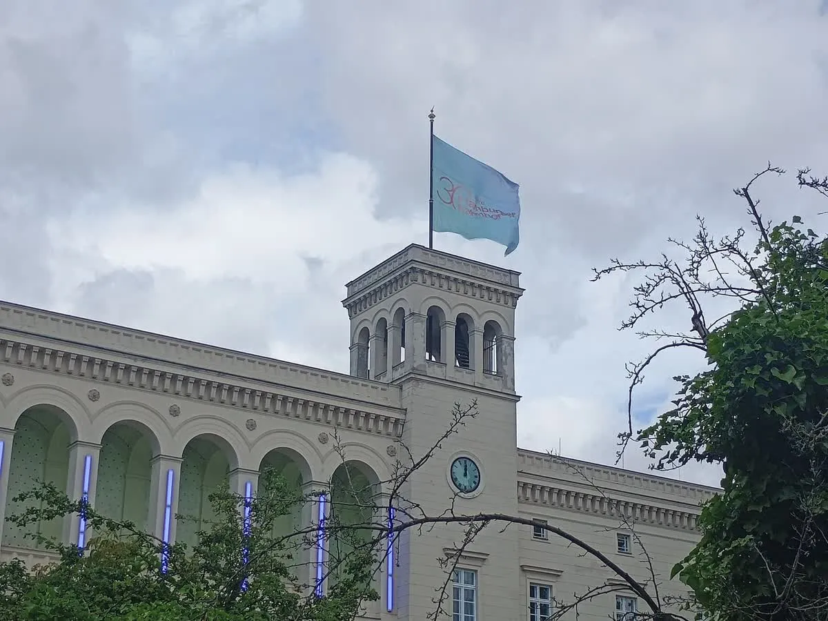 La façade de briques claires du musée Hamburger Bahnhof à Berlin, avec le drapeau bleu du musée hissé au-dessus de sa tour