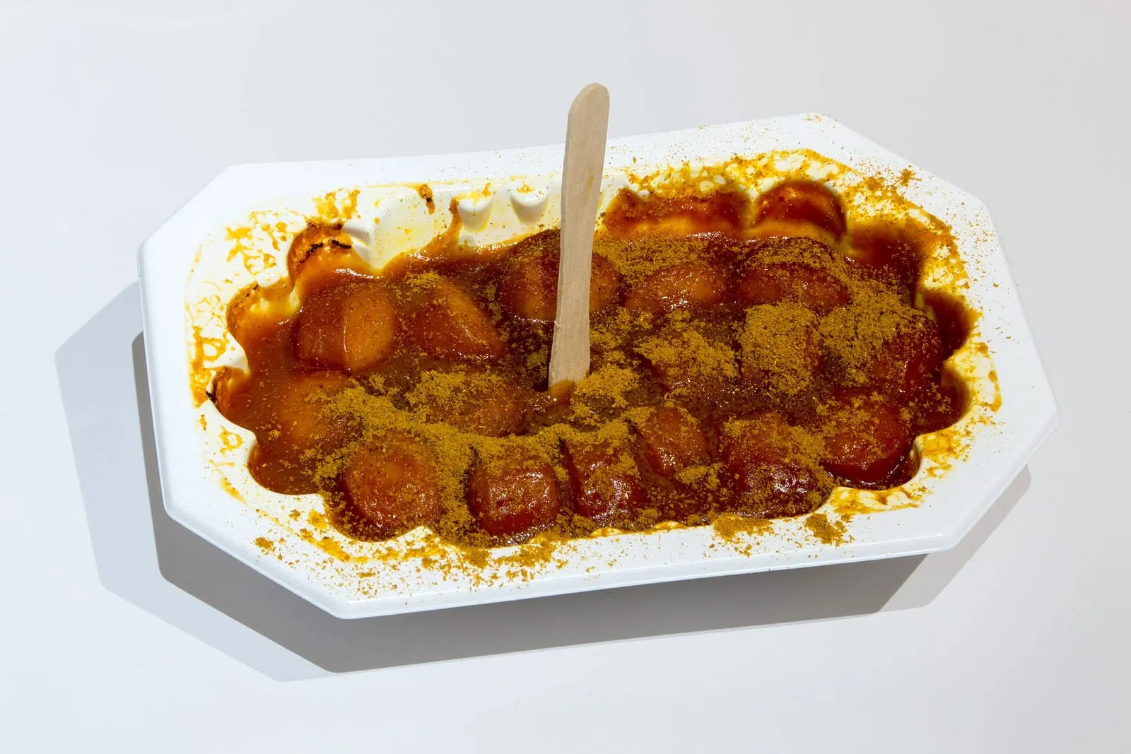 Une currywurst coupée en rondelles, nappée de sauce tomate au curry et saupoudrée de poudre de curry
