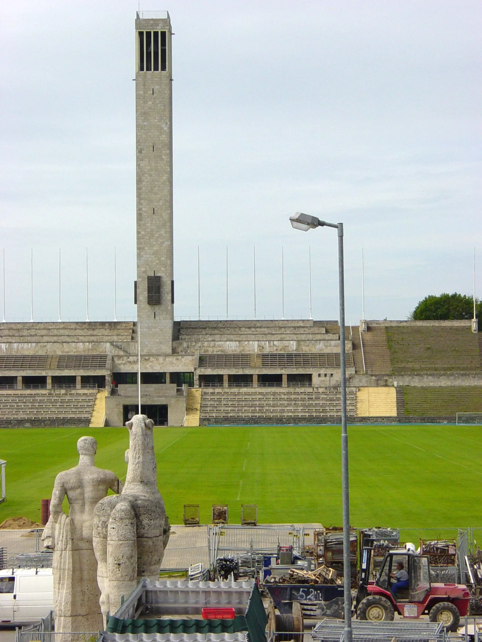 Le Maifeld vu depuis les tribunes, avec la tour de la cloche de l'Olympiapark et les sculptures de chevaux