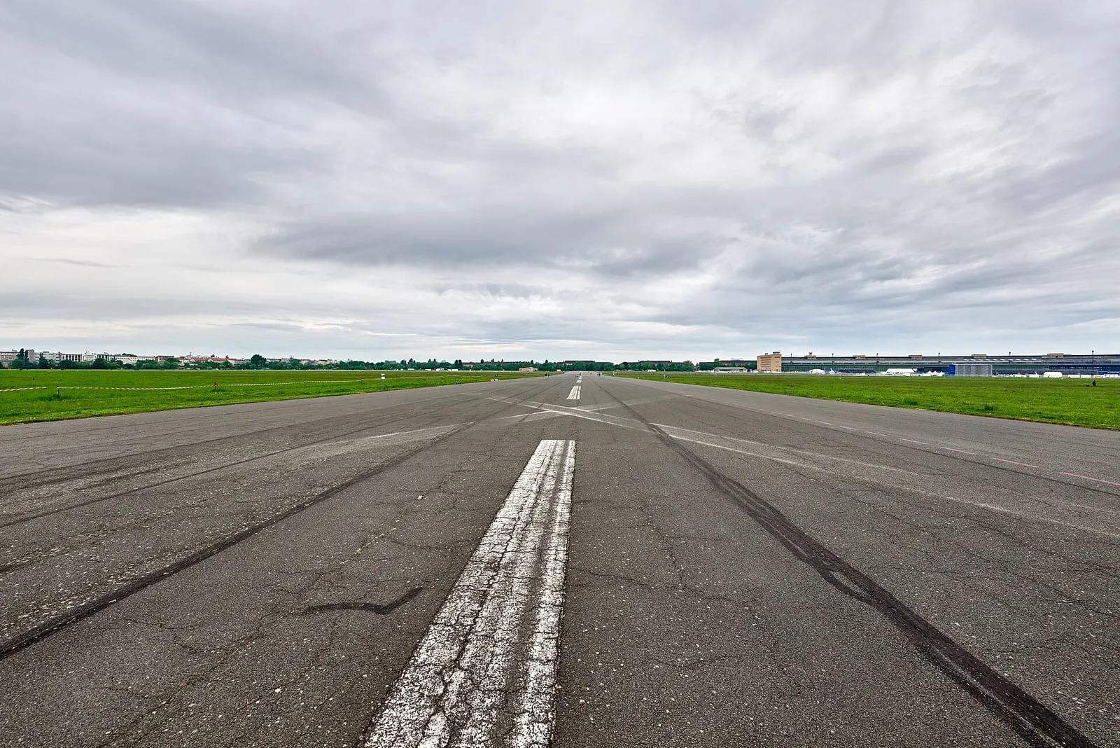 L'ancienne piste d'atterrissage du Tempelhofer Feld, longue bande d'asphalte marquée de blanc et bordée de pelouses, la ville à l'horizon