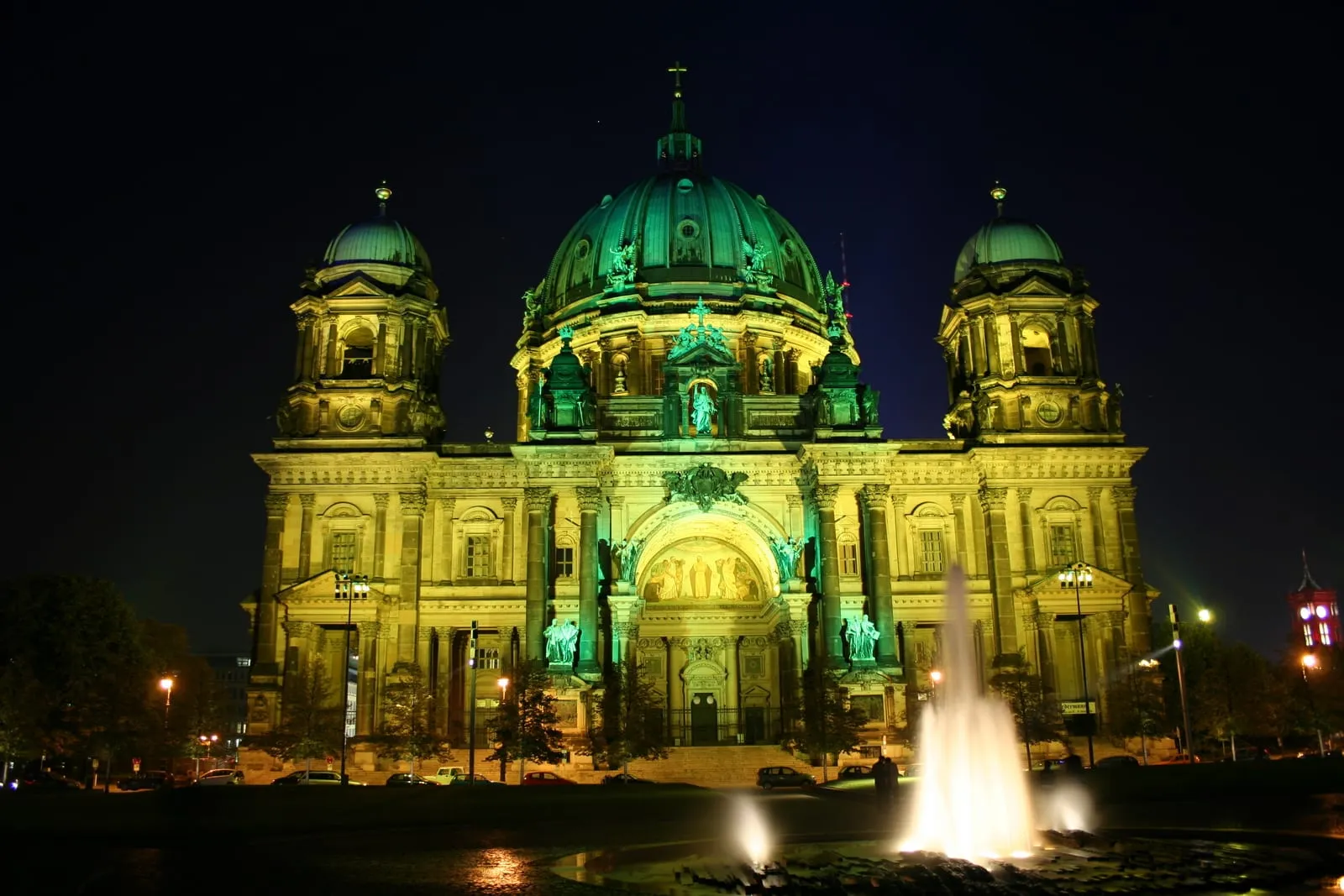 La cathédrale de Berlin illuminée en vert et jaune par une projection du Festival of Lights, avec la fontaine du Lustgarten au premier plan