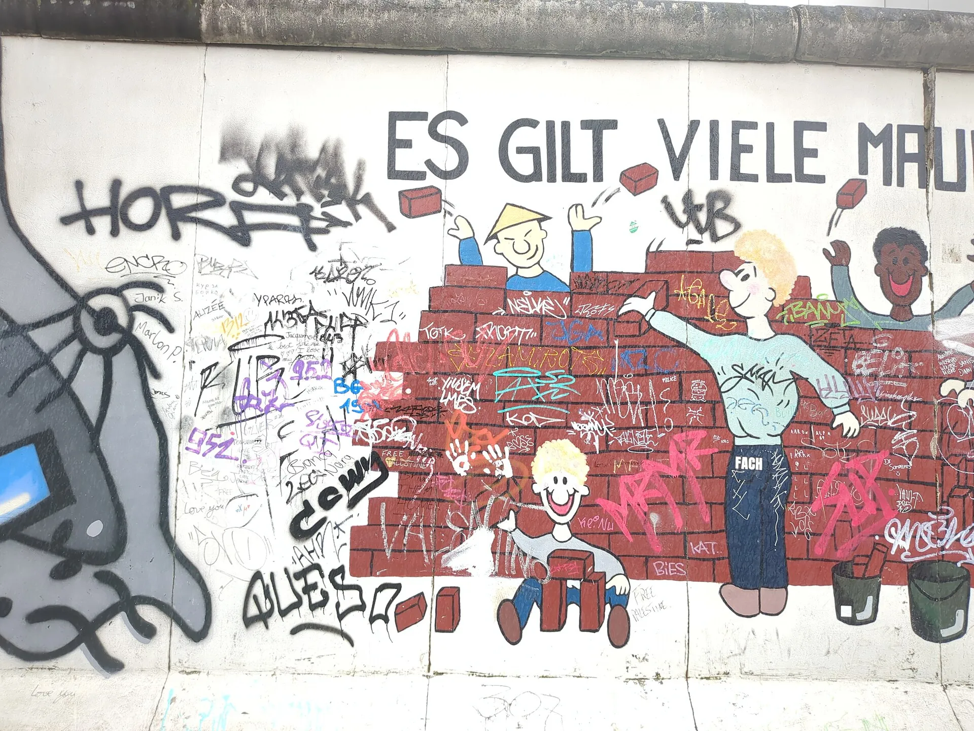 Fresque aux personnages stylisés peinte sur le mur de la East Side Gallery, la longue portion conservée du mur de Berlin à Friedrichshain