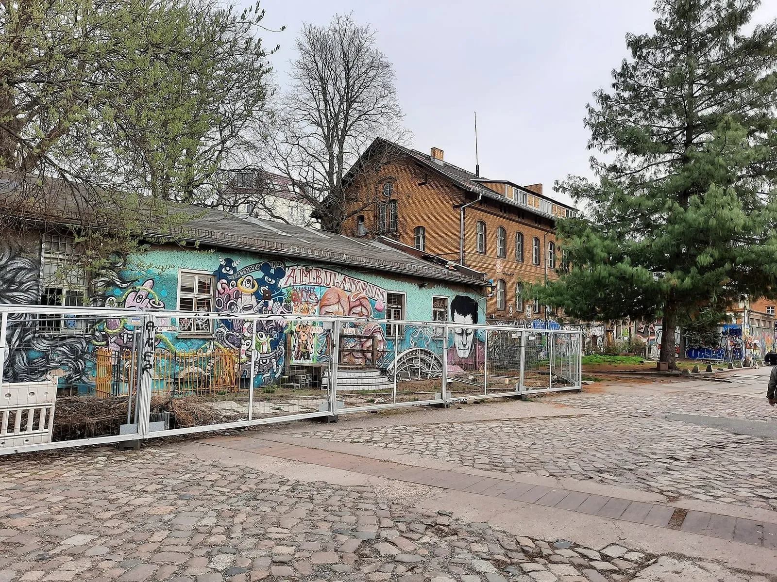 Façade d'un bâtiment du RAW-Gelände à Friedrichshain entièrement recouverte de fresques colorées, devant les anciens ateliers ferroviaires en brique