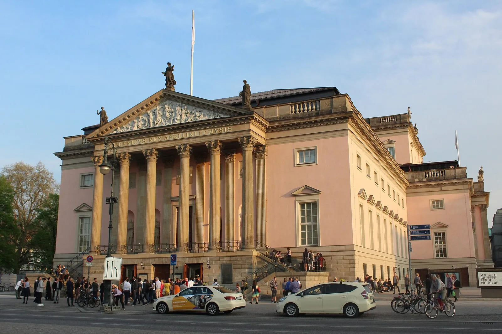 La façade rose de la Staatsoper Unter den Linden, son portique de colonnes et son fronton sculpté au soleil couchant
